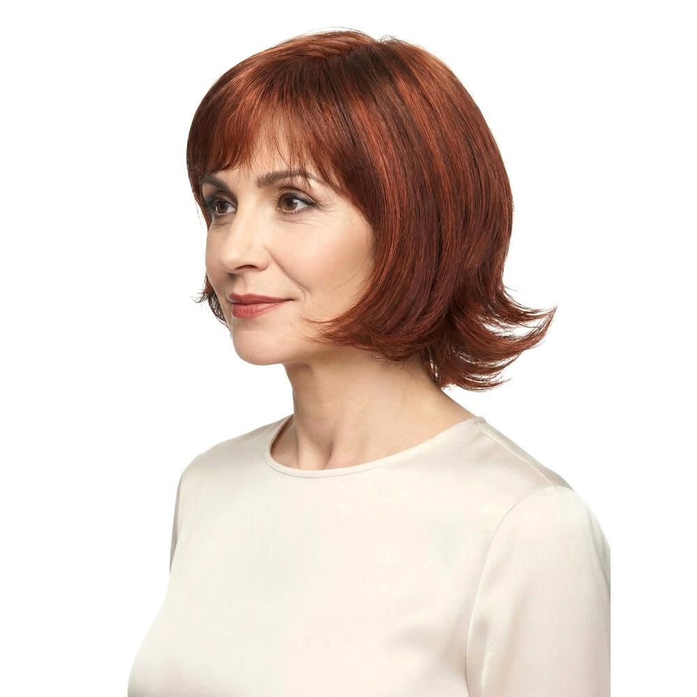 Frau mit roter Perücke MAILAND. Seitenansicht. Kurzes, gewelltes Haar. Trägt ein cremefarbenes Oberteil. Blick nach links.