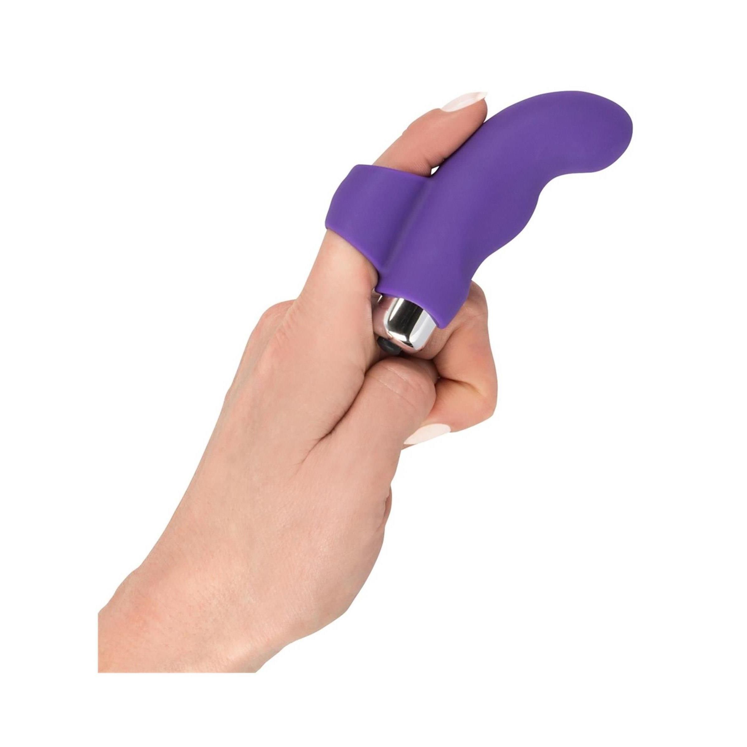 Hand mit lila Finger-Vibrator. Ringförmige Basis am Finger. Silberfarbener Vibrationskopf.
