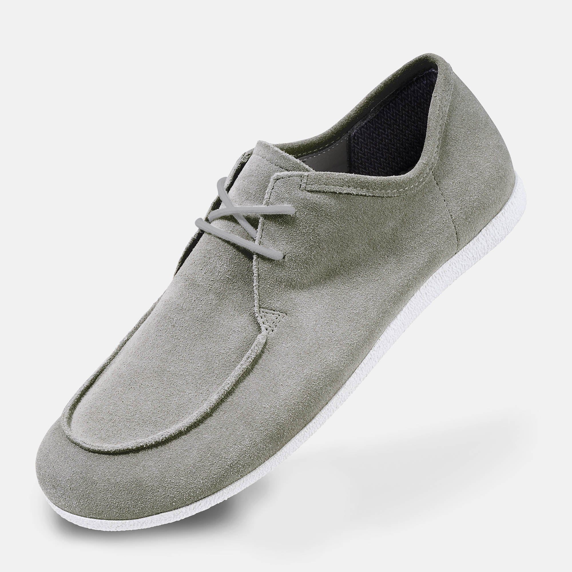 Grauer Schnürschuh mit weißer Sohle. Wildleder-Obermaterial. Breite Passform. Schuh von oben schräg.