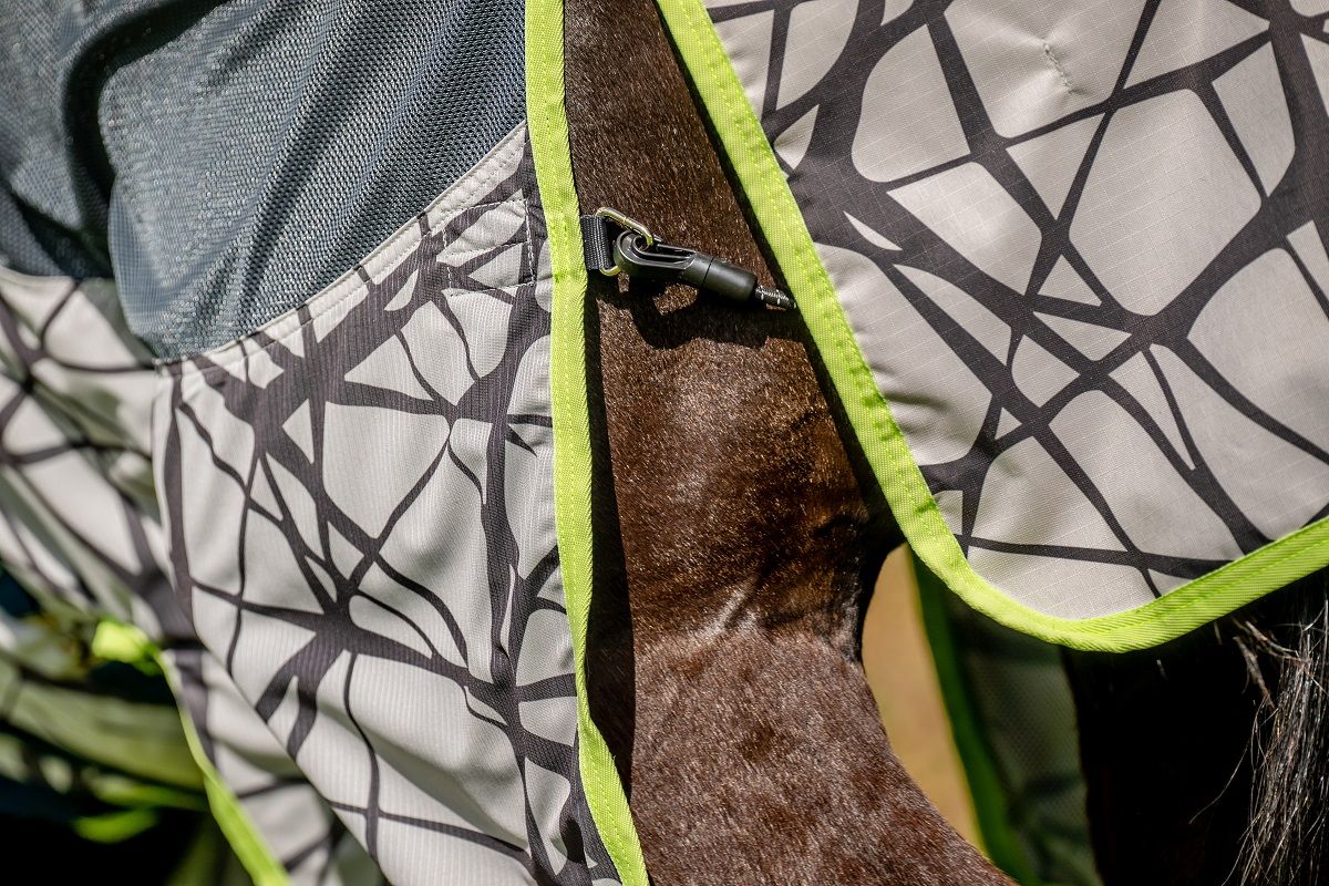 Detailansicht der Pferdedecke mit Camouflage-Muster. Grau, Schwarz und Neongrün. Mit Schnalle.