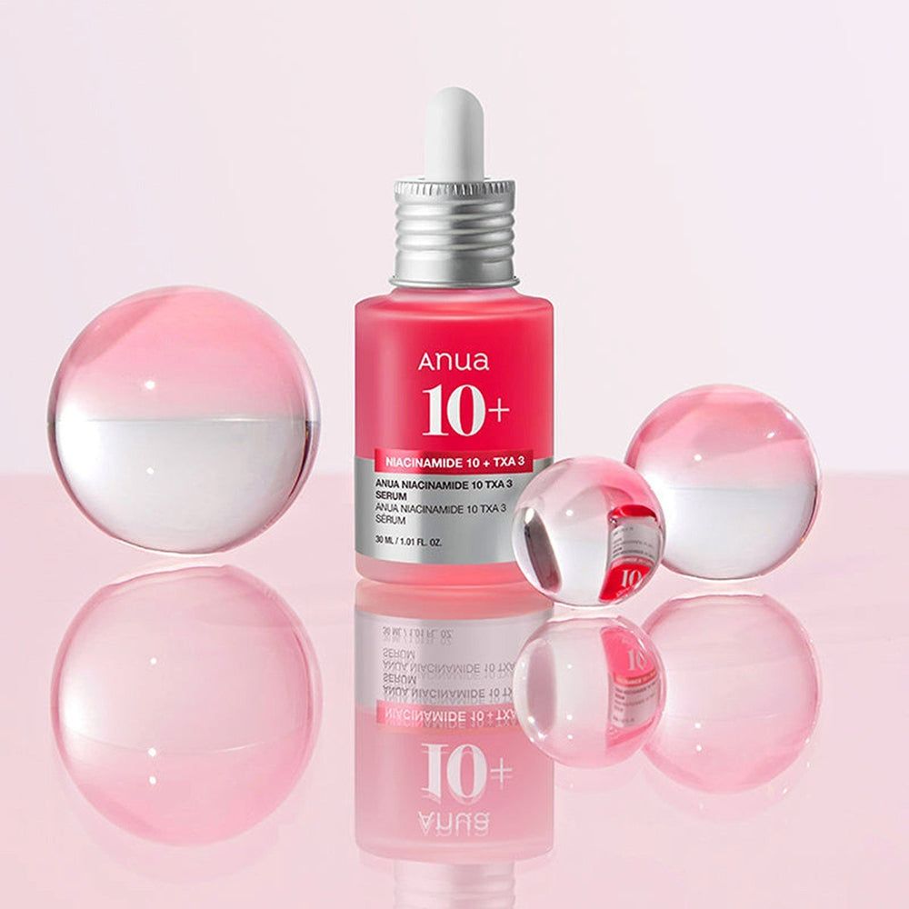 Serumflasche mit Text: Anua 10+. Niacinamid 10% + TXA 4% Serum. 30 ml. Mit rosa Kugeln.