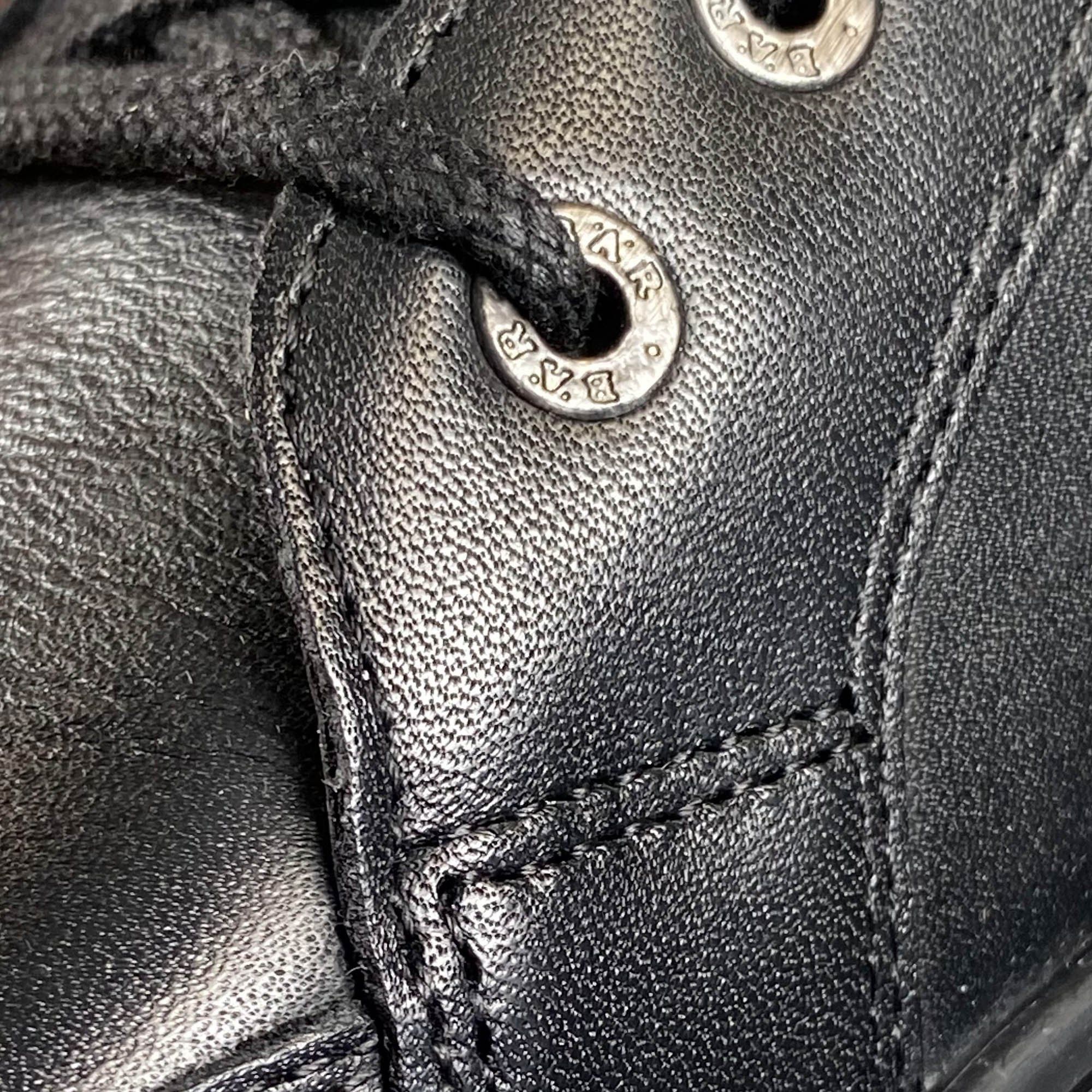 Nahaufnahme eines schwarzen Schnürschuhs. Metallösen mit Logo, Lederoptik, Schnürsenkel.