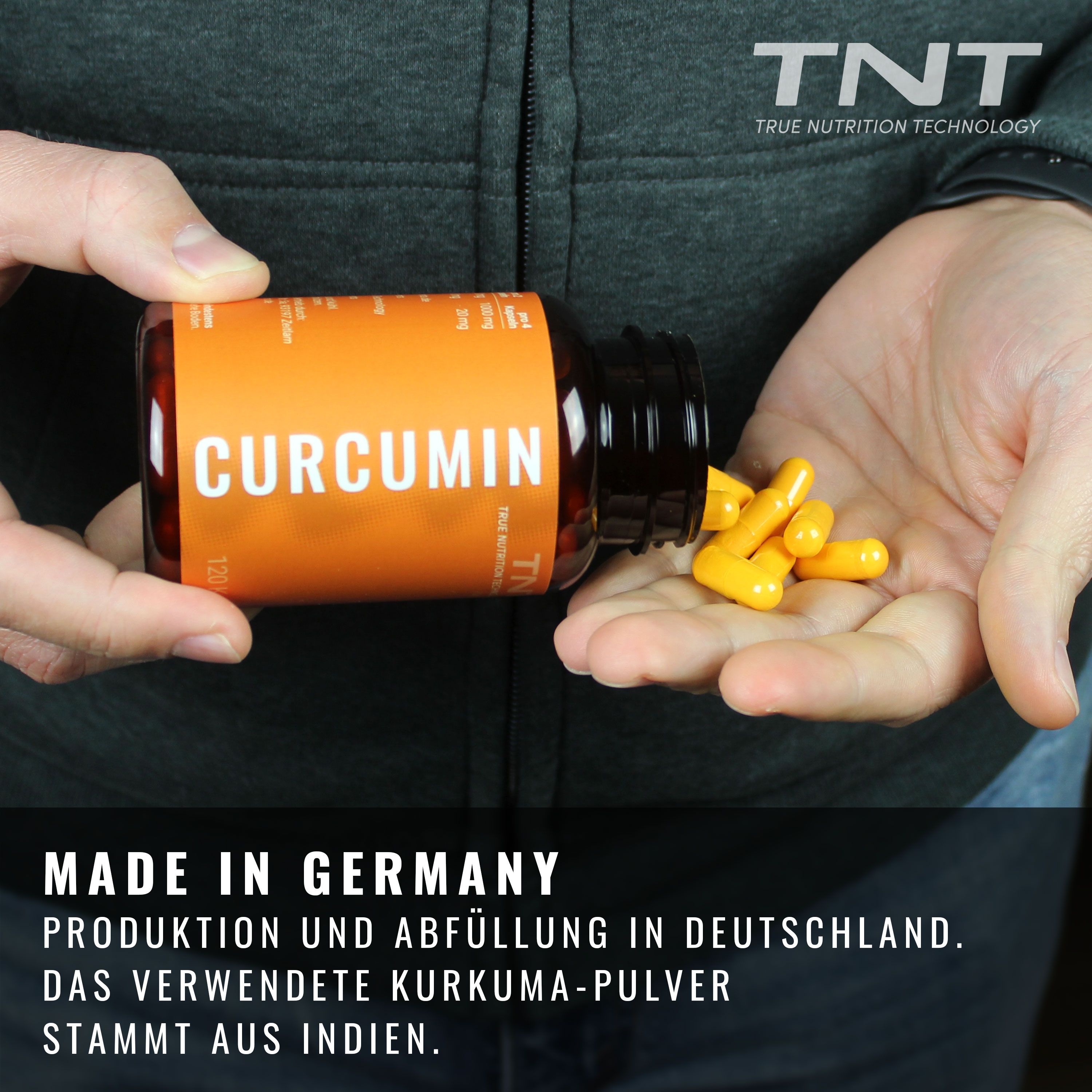 Person hält Dose und Kapseln. Dose mit CURCUMIN-Aufschrift. Gelbe Kapseln werden in die Hand gegossen.