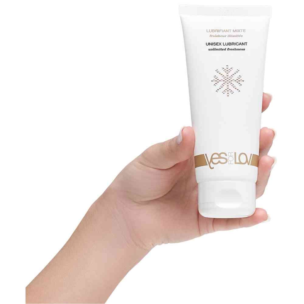 Weißes Tube mit Produkttext und Logo. Gehalten von einer Hand. Aufschrift: Unisex Lubricant unlimited freshness.
