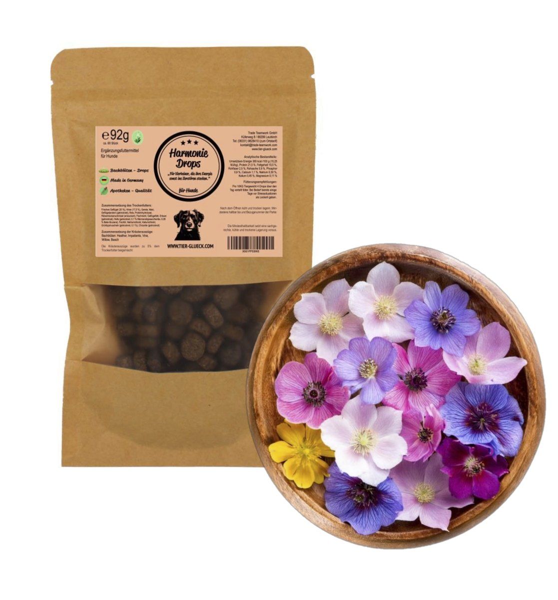 Beutel TierGlück Harmonie Drops neben einer Holzschale mit bunten Blüten. Produkt und Blüten auf weißem Hintergrund.