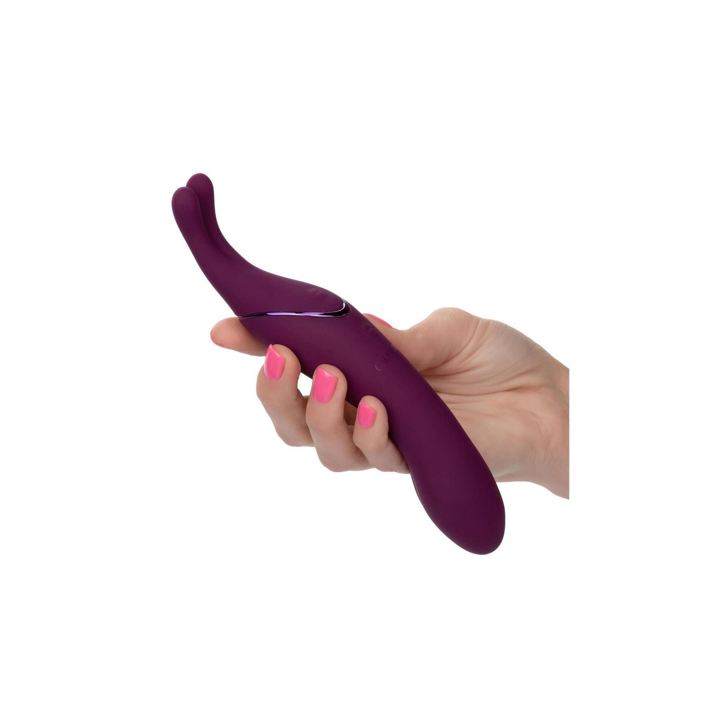 Lila Massagegerät in einer Hand gehalten. Produkt mit doppelter Spitze. Rosa lackierte Fingernägel.