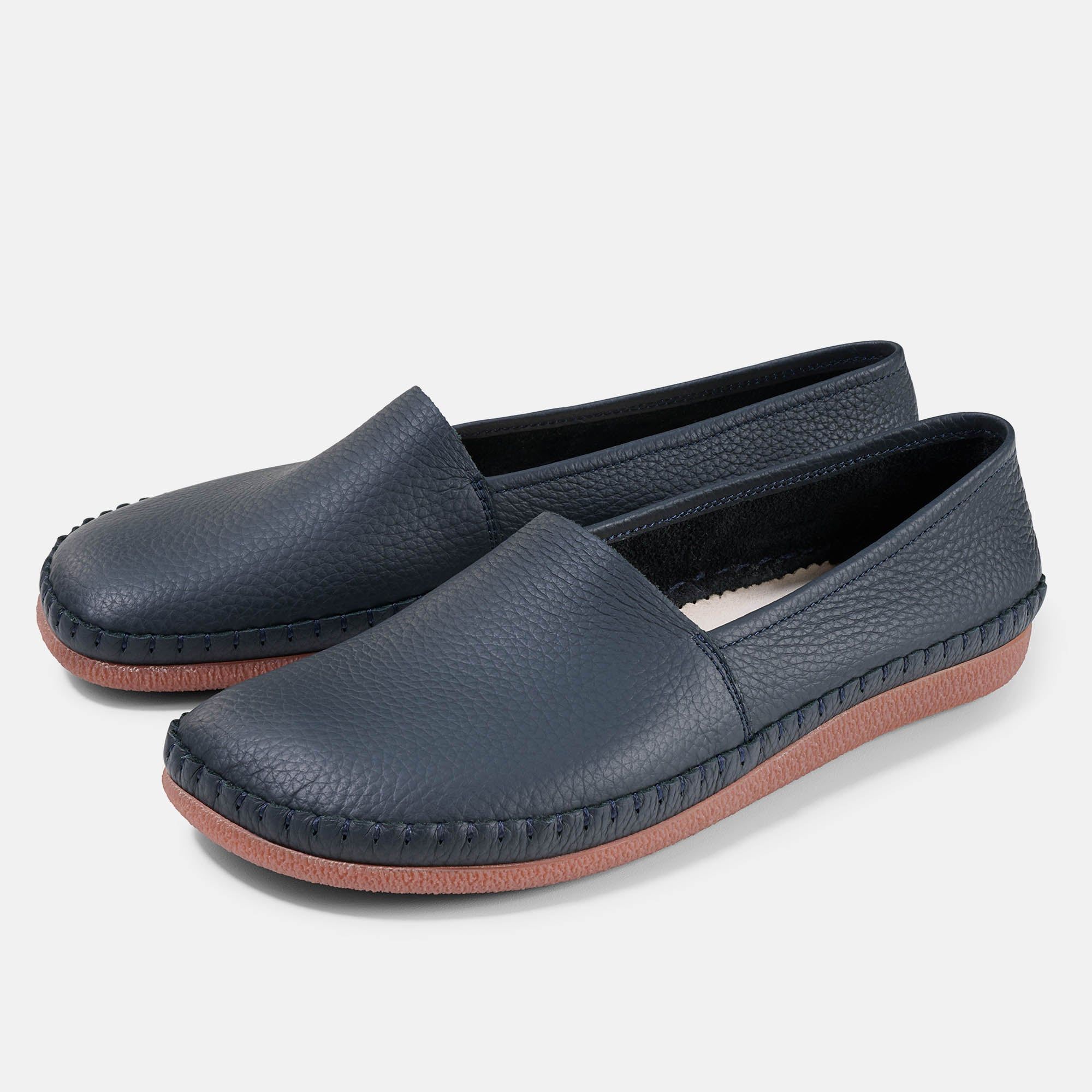 Zwei blaue Unisex-Slipper mit breiter Passform. Hellbraune Sohle, Lederoptik, quadratische Spitze, sichtbare Nähte.