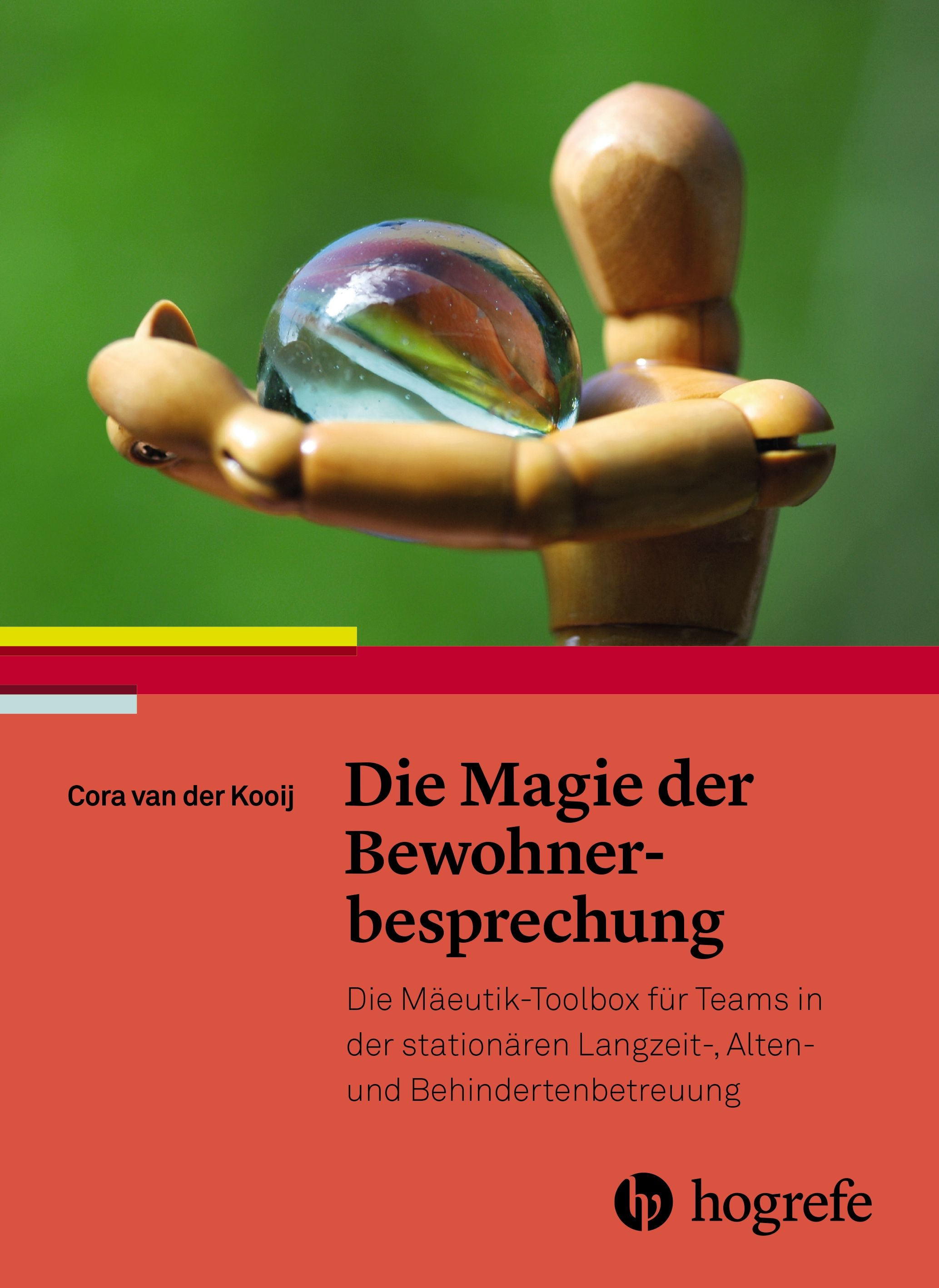 Buchcover: Titel "Die Magie der Bewohnerbesprechung". Autorin: Cora van der Kooij. Verlag: Hogrefe. Abgebildet: Holzfigur mit Glaskugel.