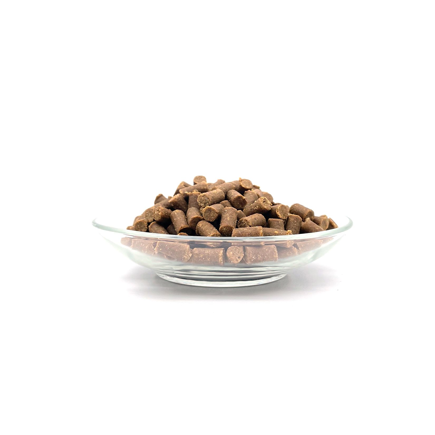 Haufen brauner, zylindrischer Snacks in einer Glasschale. Auf weißem Hintergrund.