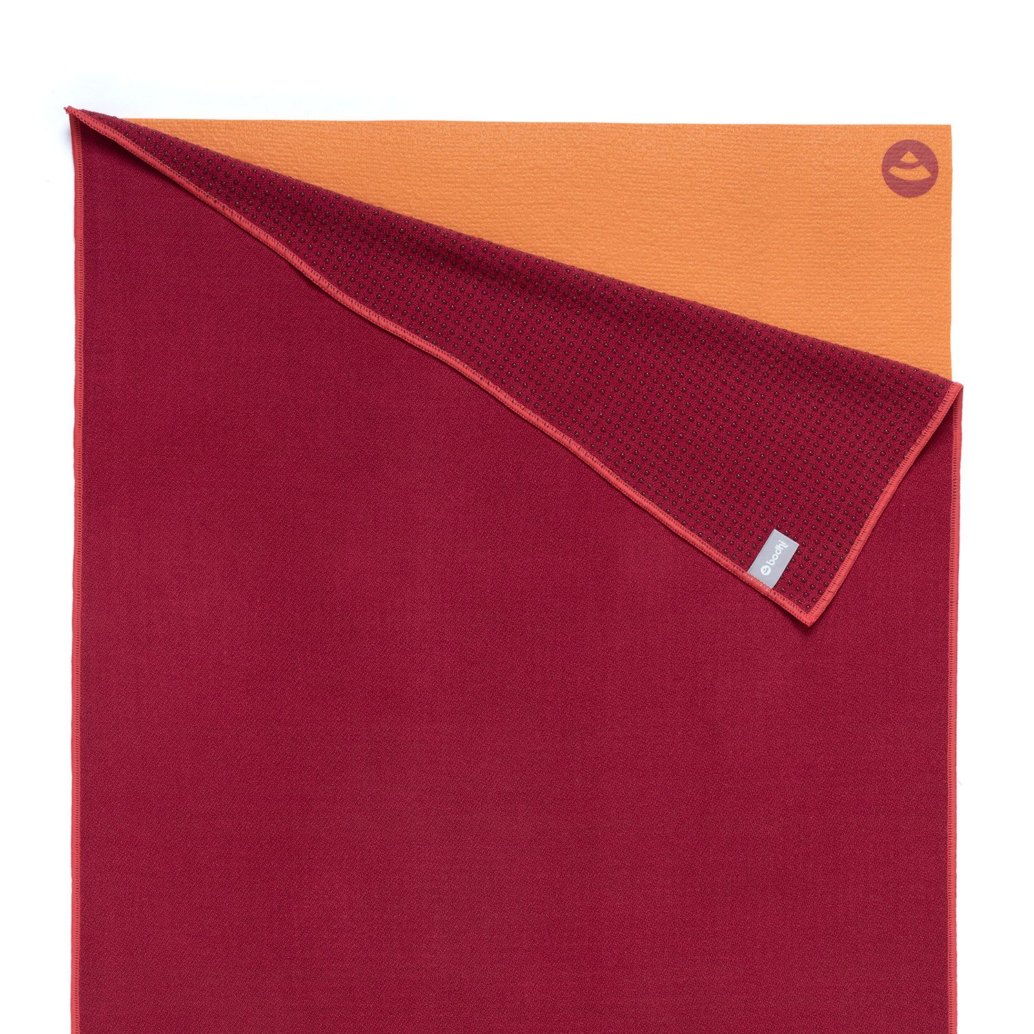 Weinrotes Yoga-Handtuch, zweifarbig. Eine Seite orange, andere weinrot mit Noppen. Logo-Detail.