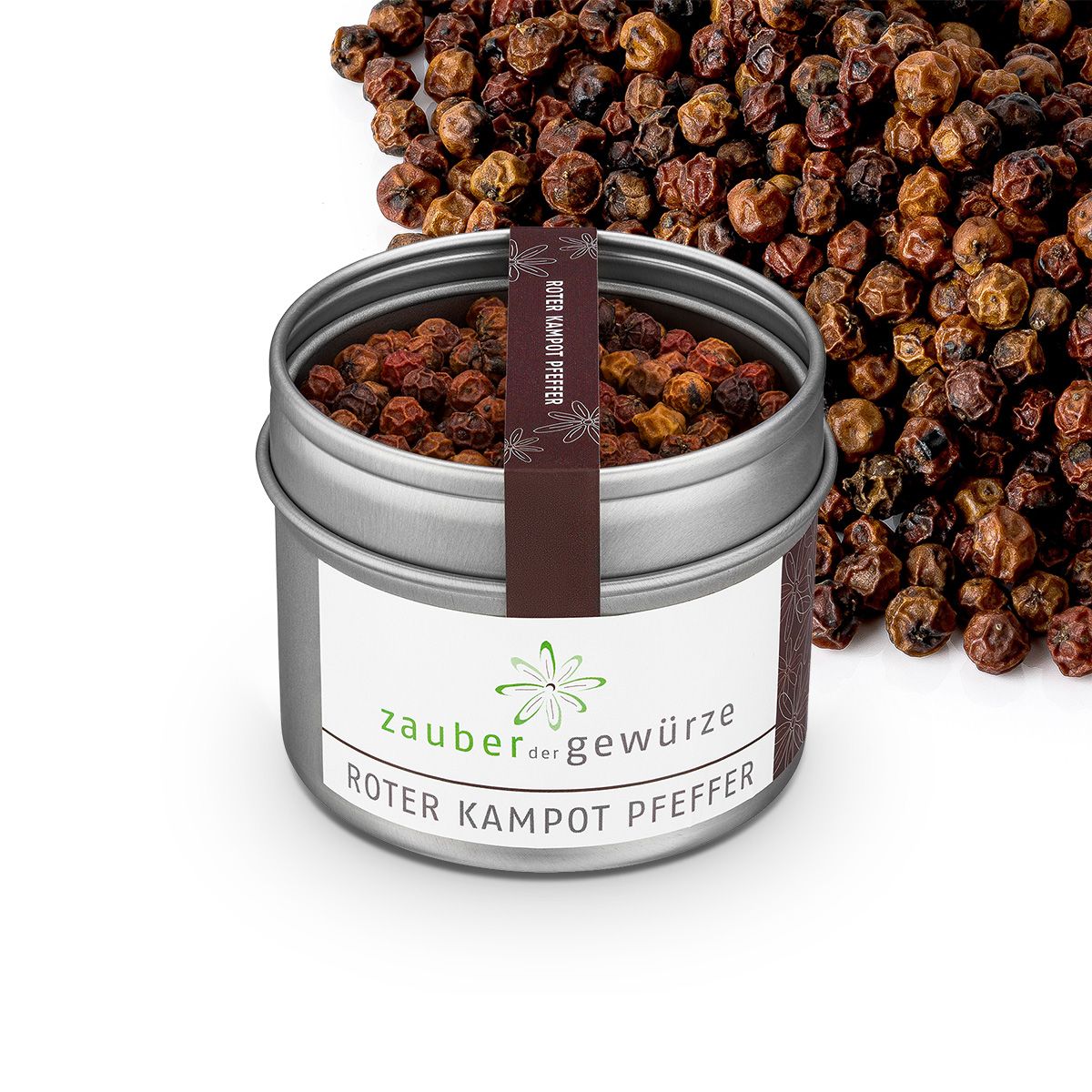 Geöffneter Metallbehälter mit rotem Kampot Pfeffer. Etikett mit "Zauber der Gewürze" und "Roter Kampot Pfeffer". Pfefferkörner verstreut.