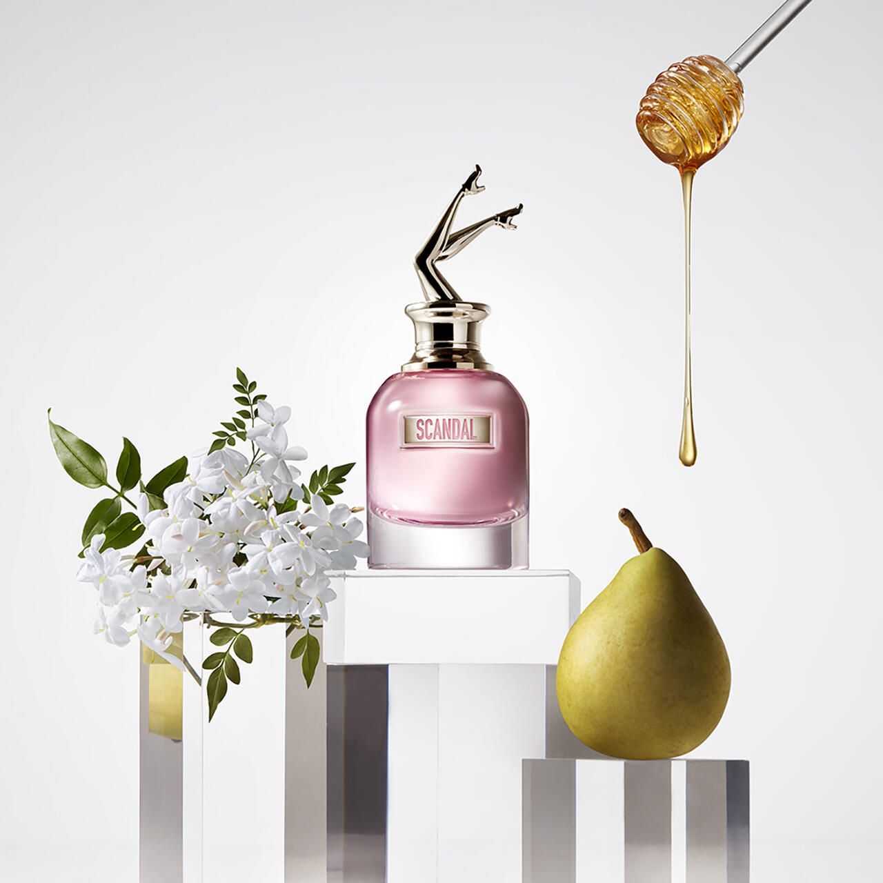 Parfumflasche, Honig, Birne und Blumen auf Podesten. Flasche mit Anhänger. Aufschrift: SCANDAL.