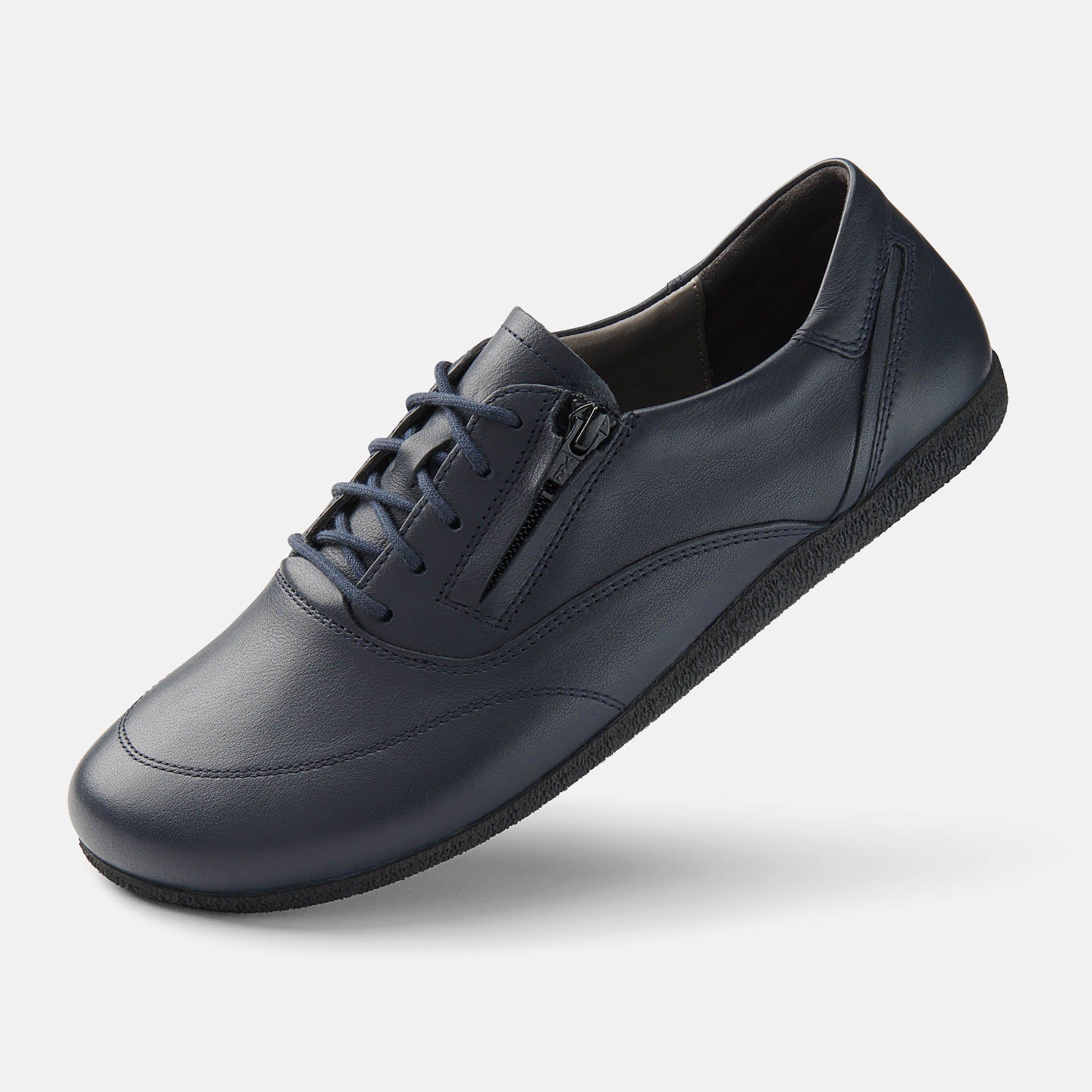 Blauer Lederschnürschuh mit Reißverschluss. Breite Passform. Flache Sohle. Hellgrauer Hintergrund. Schuh leicht geneigt.