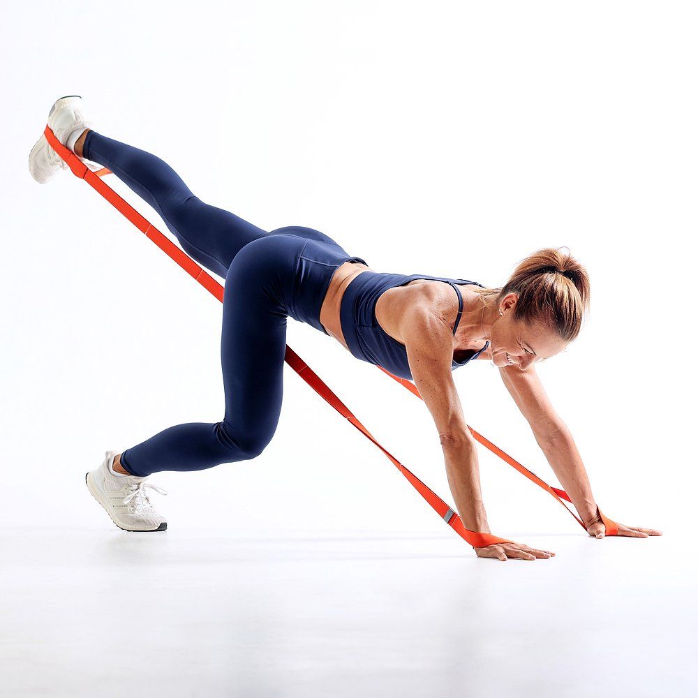 Eine Frau in Fitnesskleidung liegt auf dem Boden und trainiert mit einem orangefarbenen FLEXVIT Multi-Band.