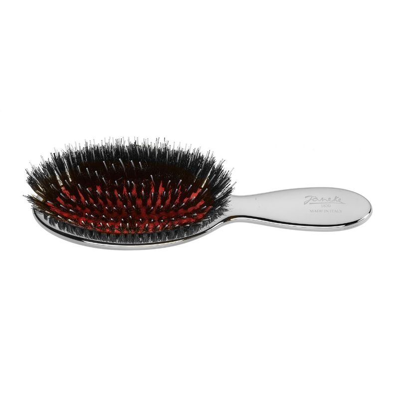 Kleine, ovale Haarbürste mit silberfarbenem Griff. Schwarze Borsten, roter Untergrund. Marke Janeke.