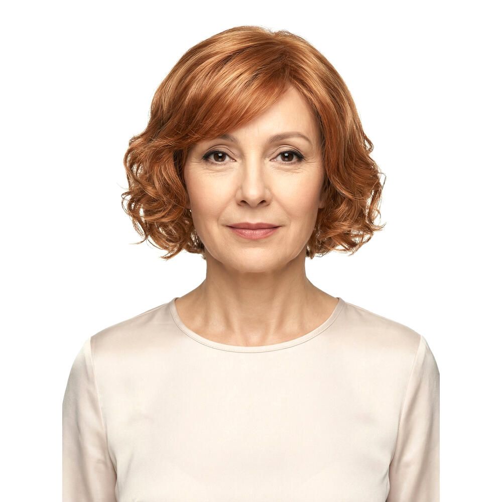 Frau mit rotblonder Perücke. Welliges Haar, Pony. Frontalansicht, helles Oberteil.