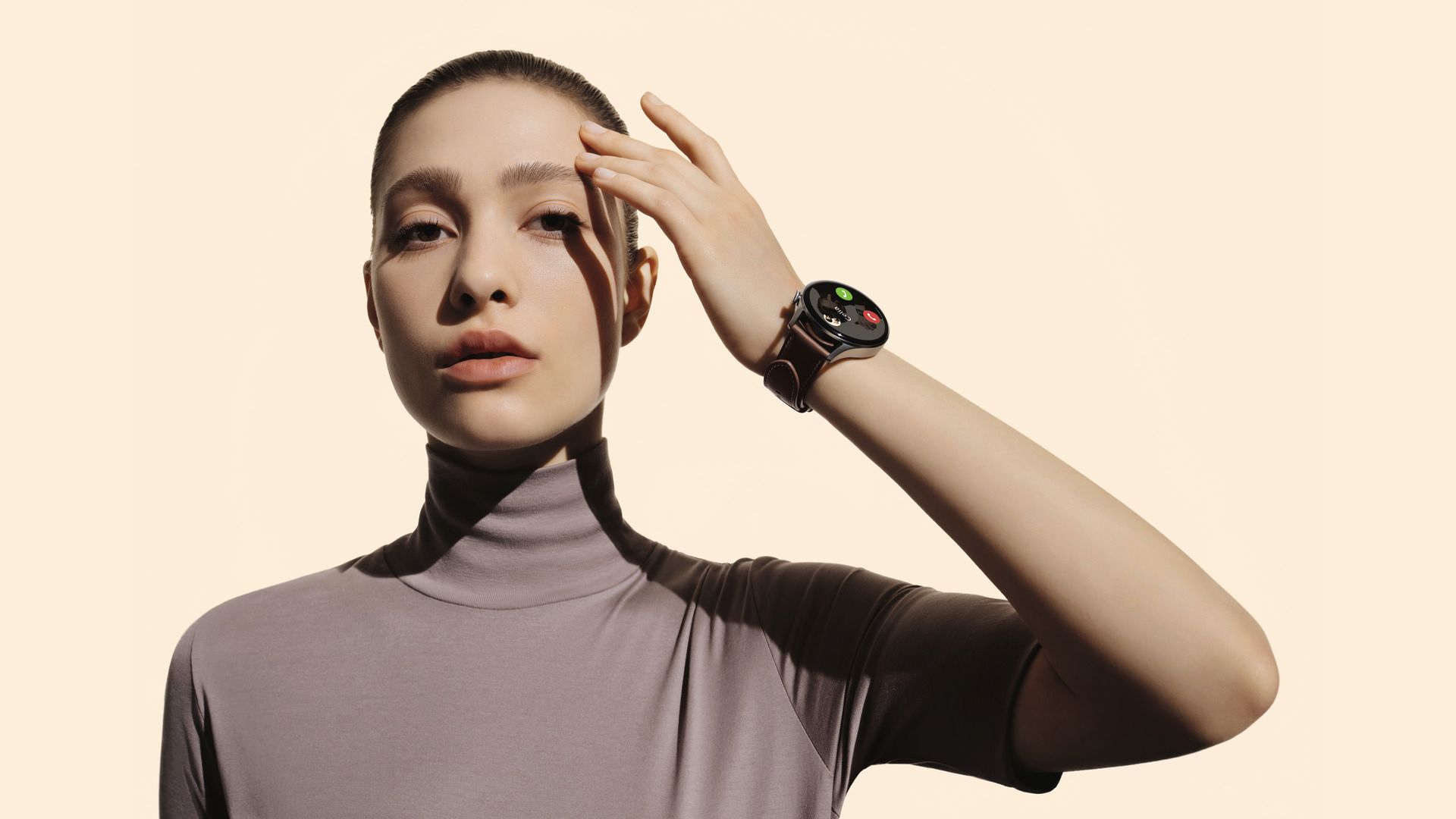 Frau mit Smartwatch am Handgelenk. Graues Oberteil, Uhr mit dunklem Zifferblatt.