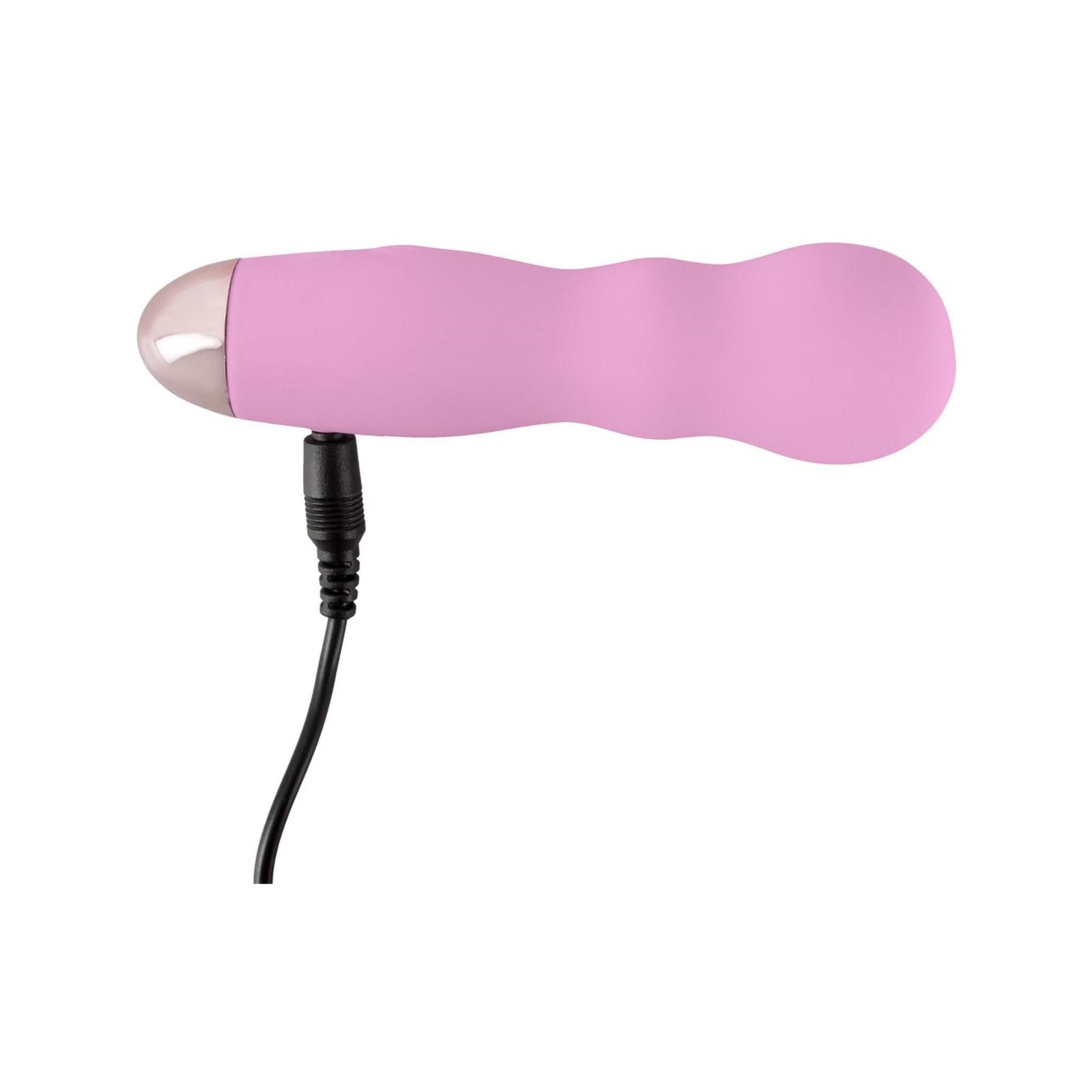 Rosa Mini-Vibrator mit angeschlossenem Ladekabel. Zylindrische Form, silberfarbene Spitze. Schwarzes Kabel.