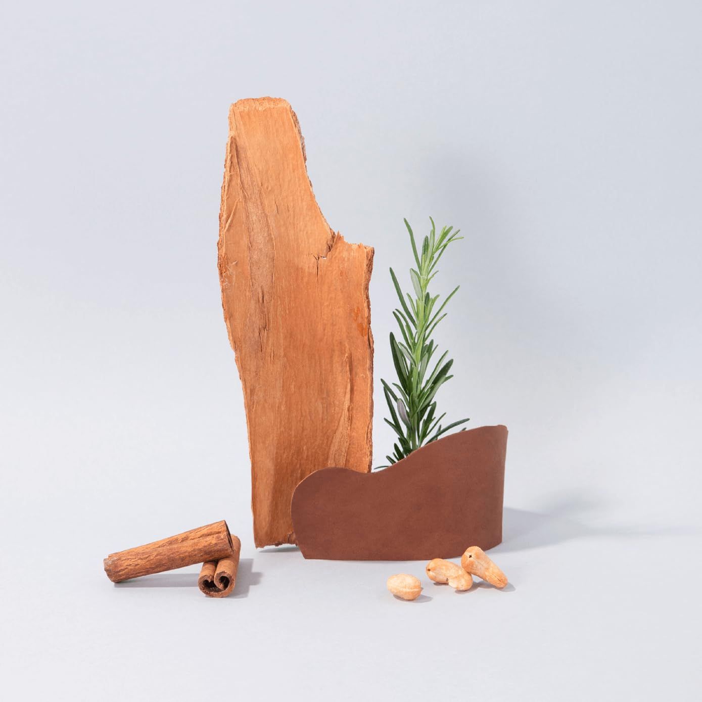 Arrangement aus Holz, Zimtstangen, Rosmarin und Mandeln auf grauem Hintergrund.