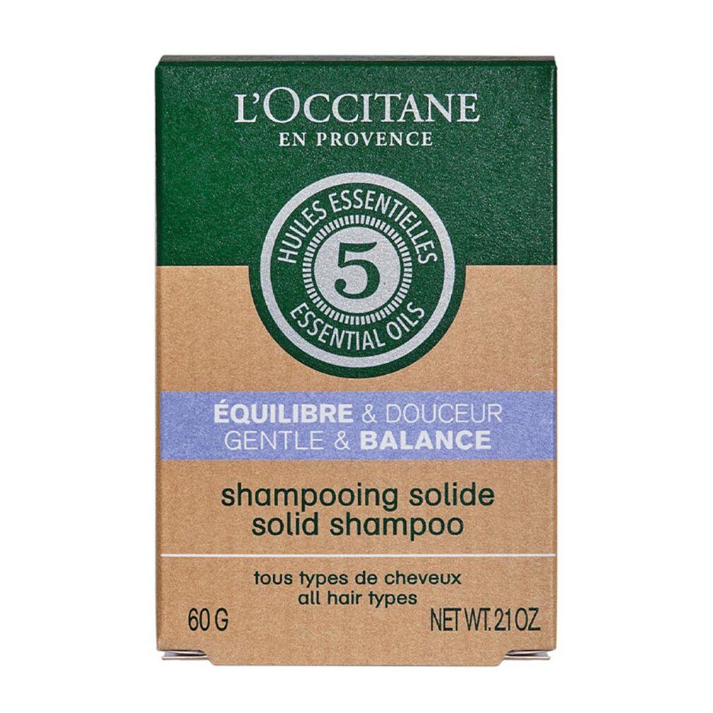 Kartonverpackung mit grünem Deckel und brauner Basis. 'L'Occitane en Provence' und '5 Essential Oils'. 'Équilibre & Douceur' und 'Shampooing Solide'.