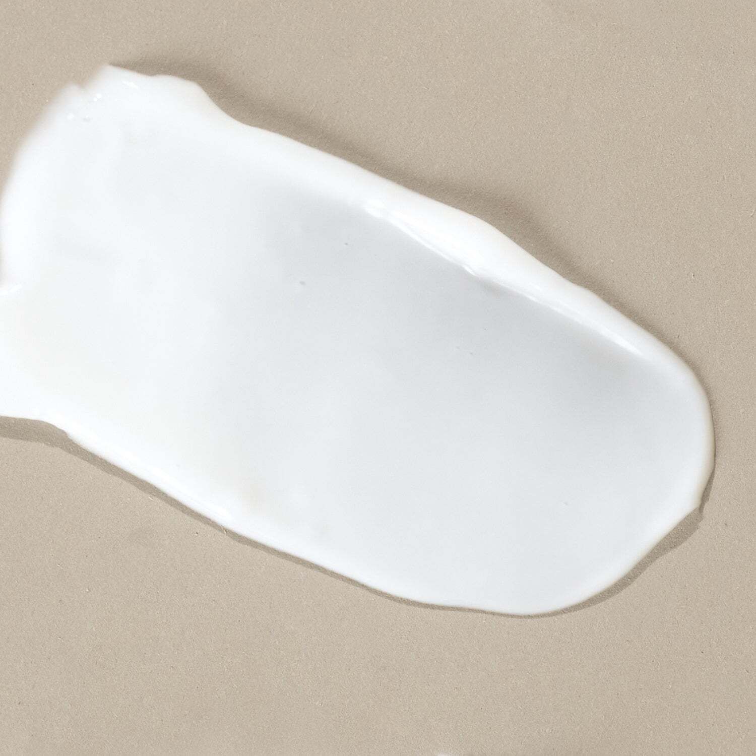 Weißer Cremekleck auf beigem Untergrund. Textur sichtbar.