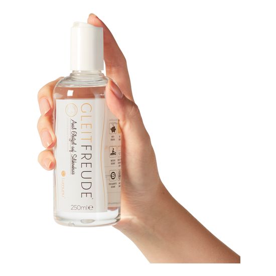 Eine Hand hält eine Flasche mit klarer Flüssigkeit und weißem Deckel. Aufschrift: Gleitfreude, Anal Gleitgel auf Silikonbasis, 250ml.