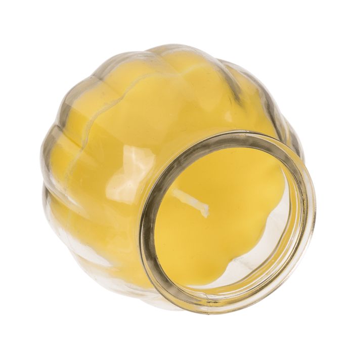 Gele kaars in glas. Gegolfde vorm. Transparante glazen pot. Bovenaanzicht.