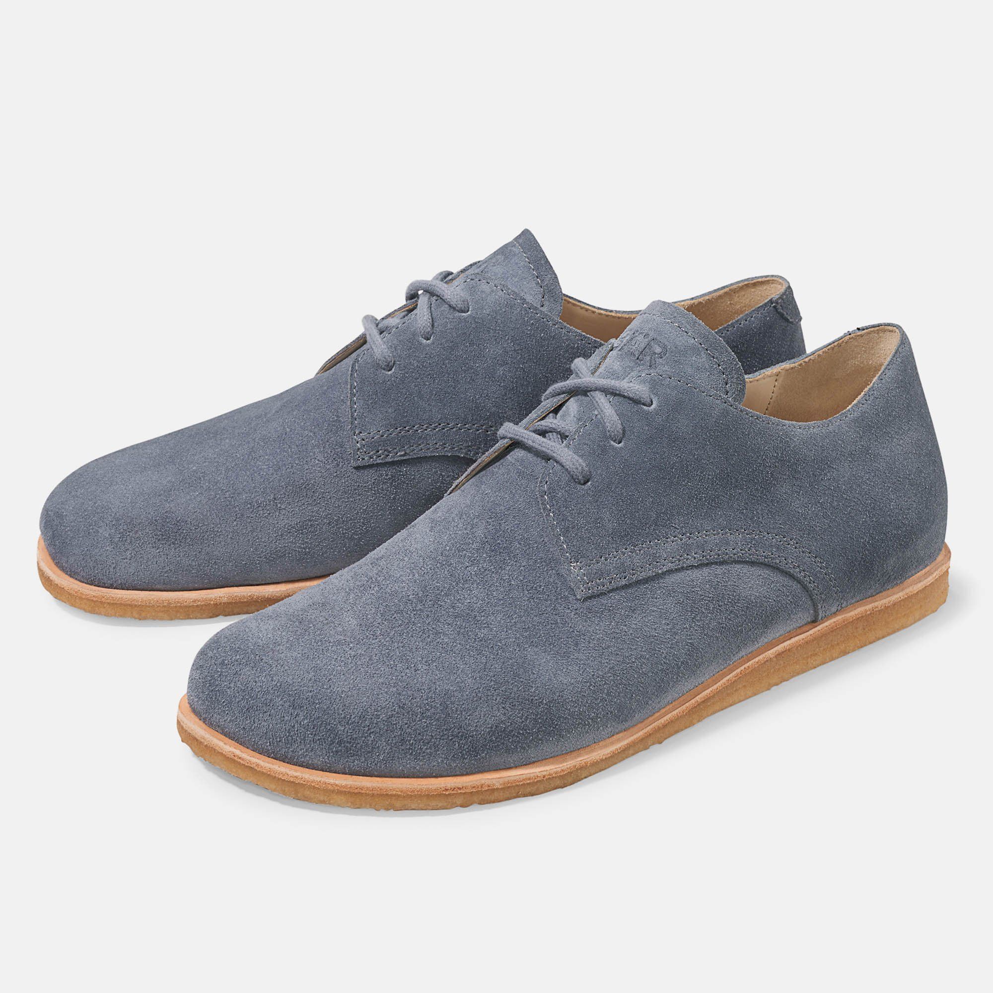 Zwei graue Schnürschuhe mit hellbrauner Sohle. Aus Wildleder.