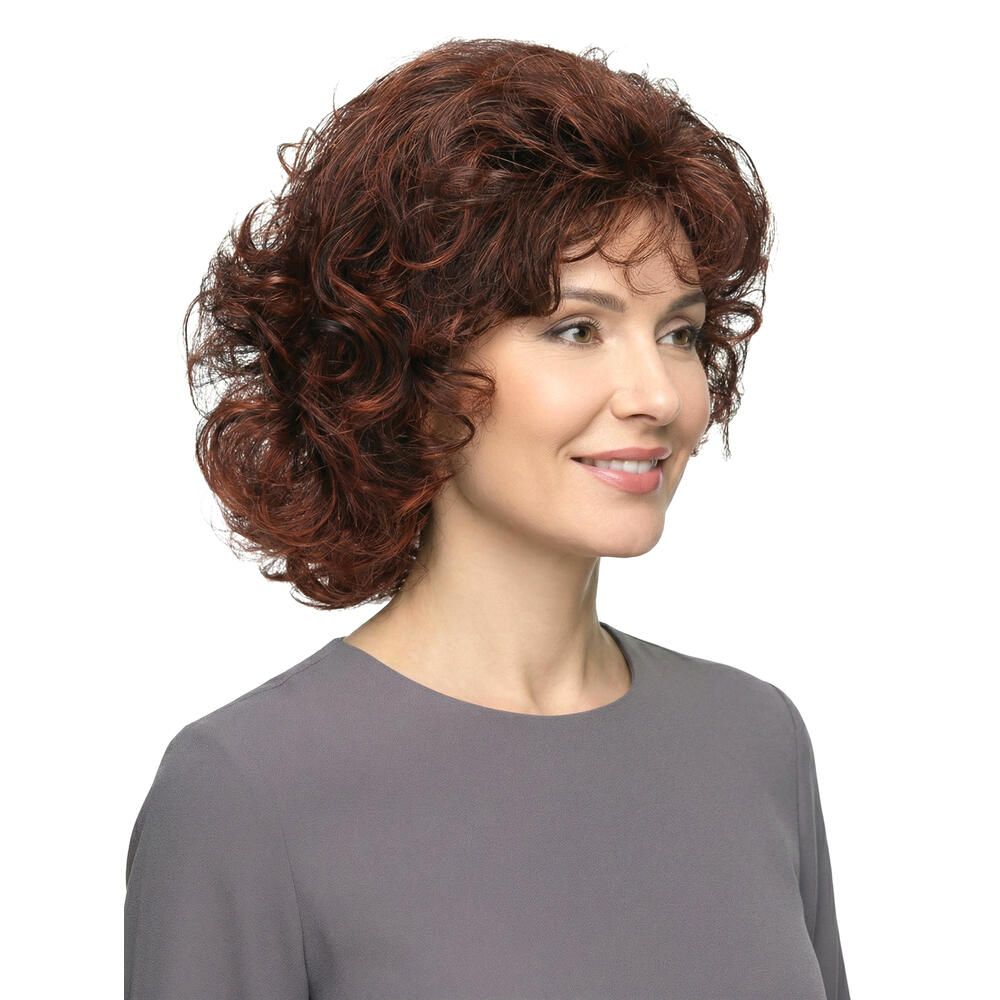 Frau mit brauner, lockiger Perücke. Dreiviertelansicht. Graues Oberteil. Weißer Hintergrund.