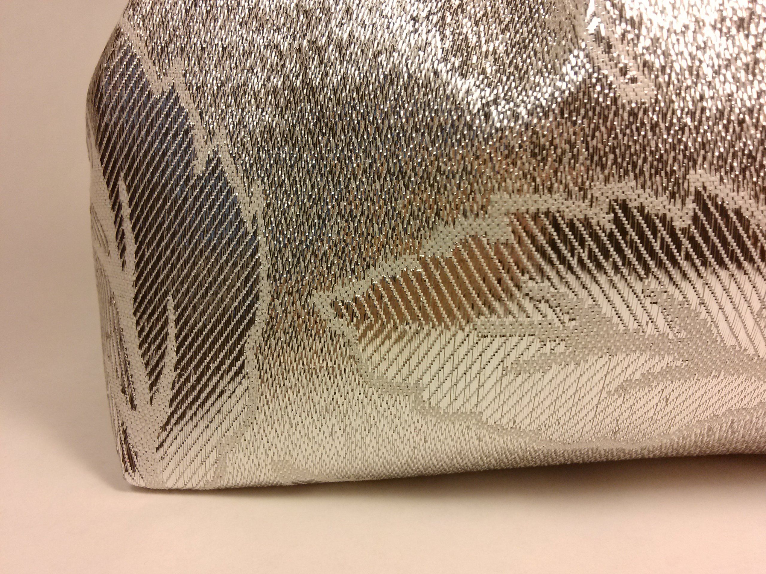 Silberfarbene Tasche mit floralem Muster. Nahaufnahme der Ecke.