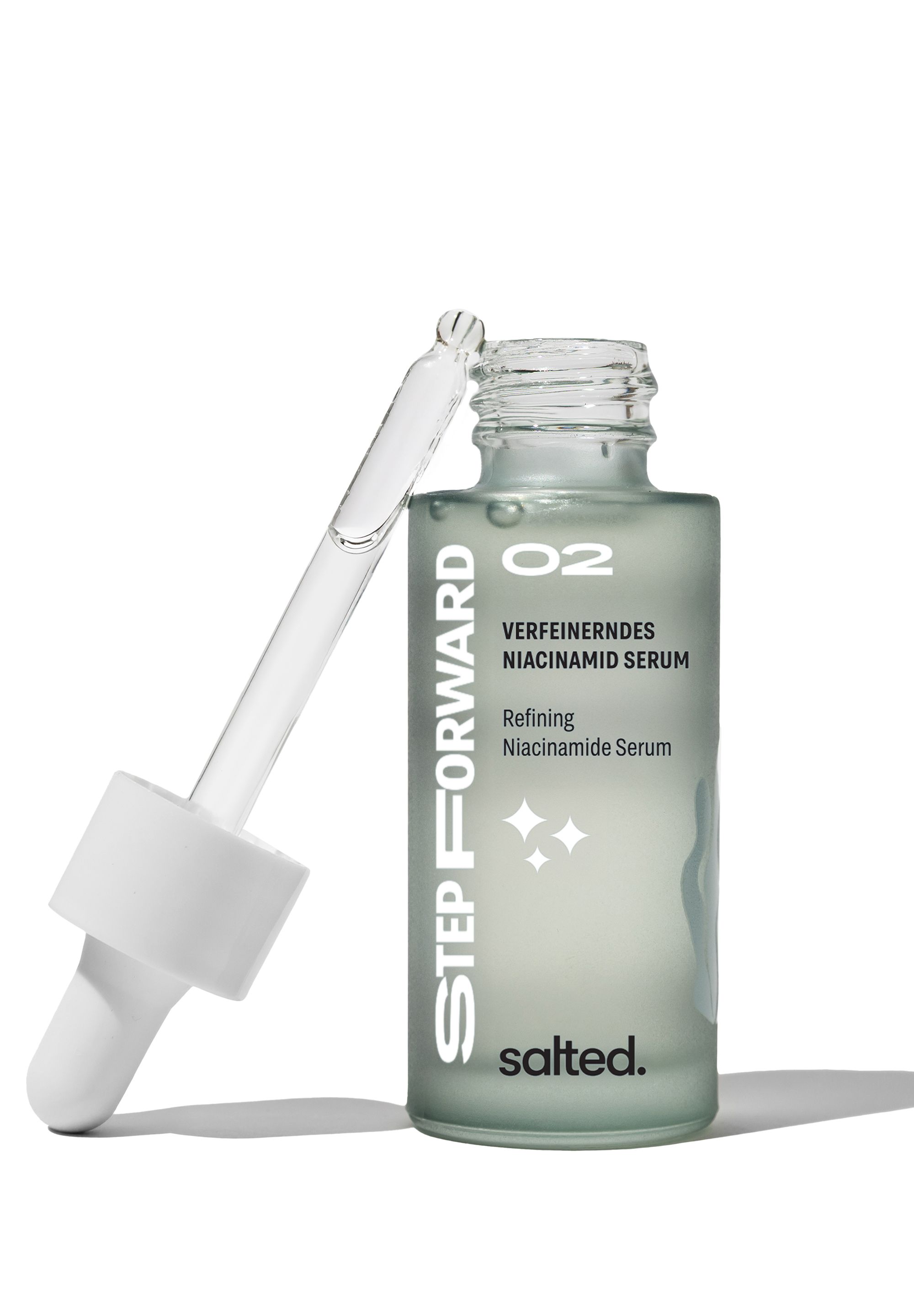 Grüne Glasflasche mit Pipette. Aufschrift: Verfeinerndes Niacinamid Serum, salted. Pipette liegt daneben.