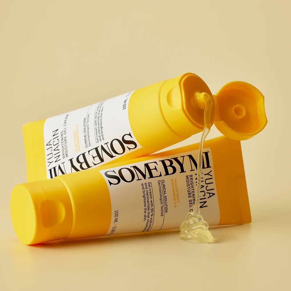 Zwei gelbe Tuben SOME BY MI Yuja Niacin. Eine Tube geöffnet, Gel tritt aus. Auf hellem Hintergrund.