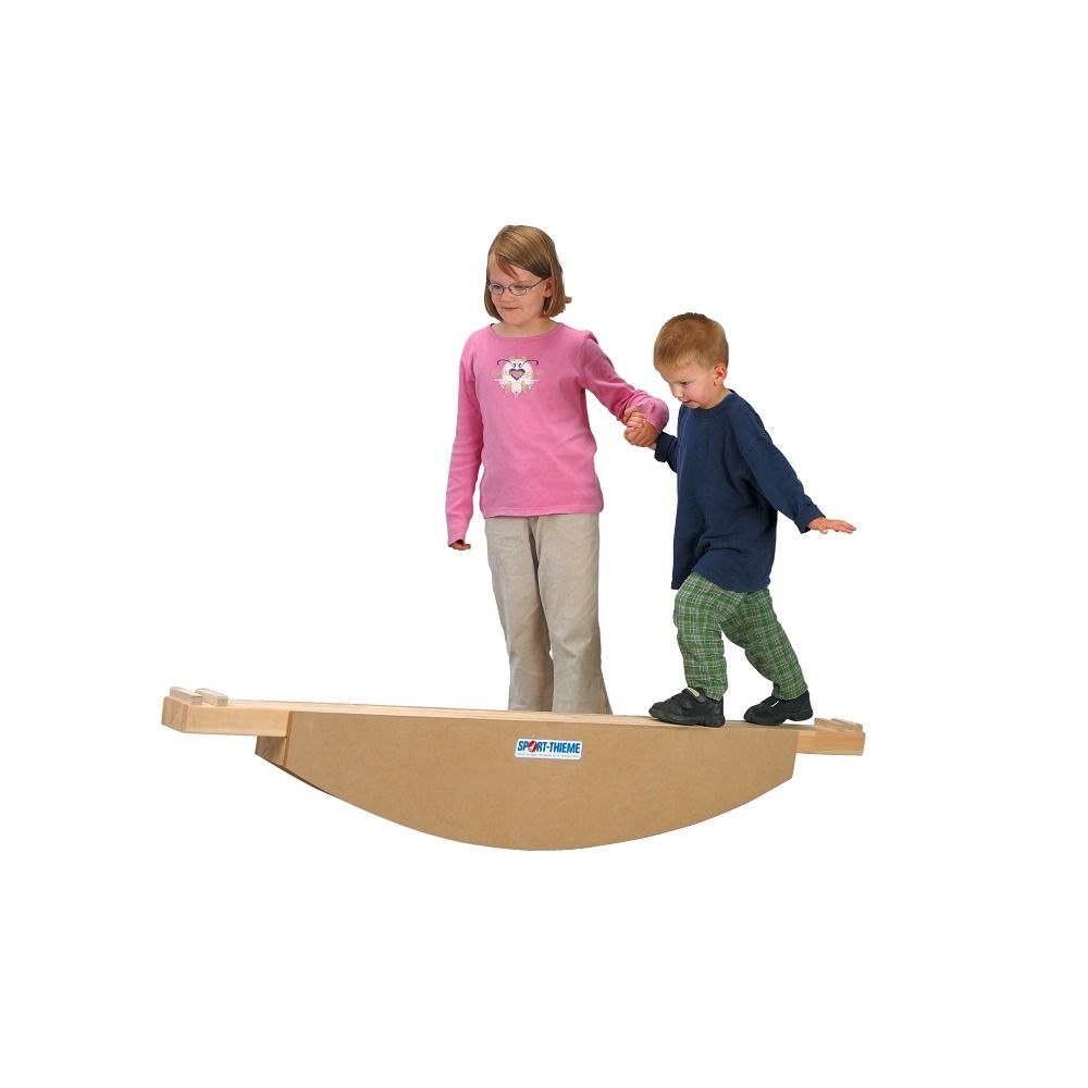 Zwei Kinder auf einer Holzwippe. Die Wippe hat die Aufschrift Sport-Thieme. Ein Kind steht, das andere geht. Beide werden von Erwachsenen begleitet.