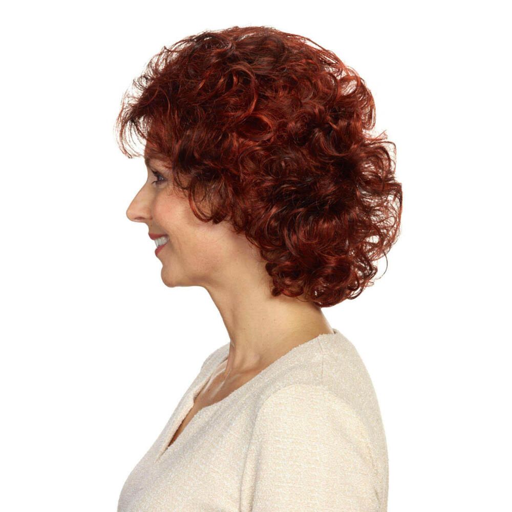 Profil einer Frau mit roter, lockiger Perücke. Sie trägt ein cremefarbenes Oberteil.