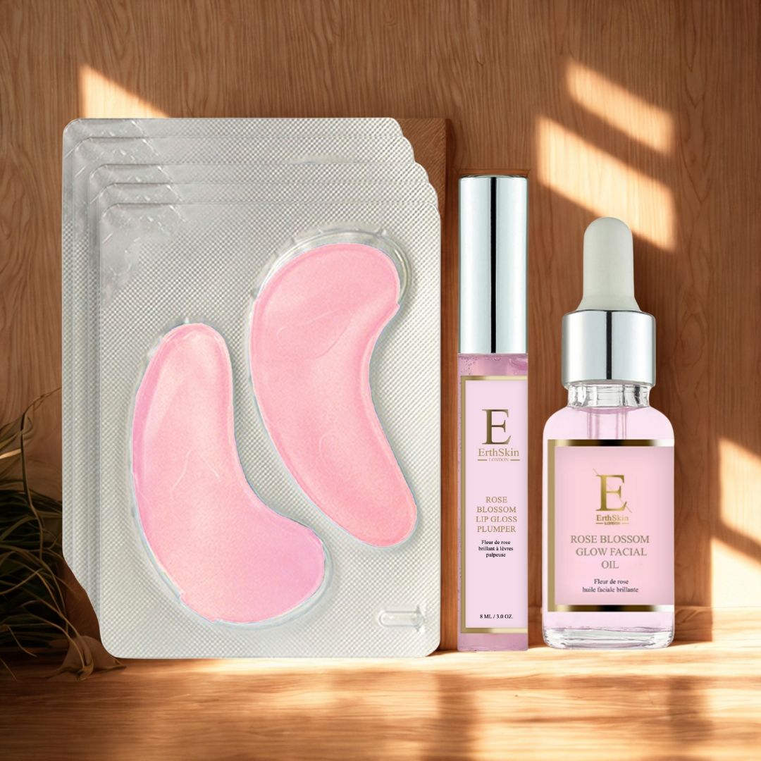 Rosa Augenpads, Lipgloss und Gesichtsöl. Augenpads in Blisterverpackung. Lipgloss und Öl mit "E"-Logo. Holzuntergrund.