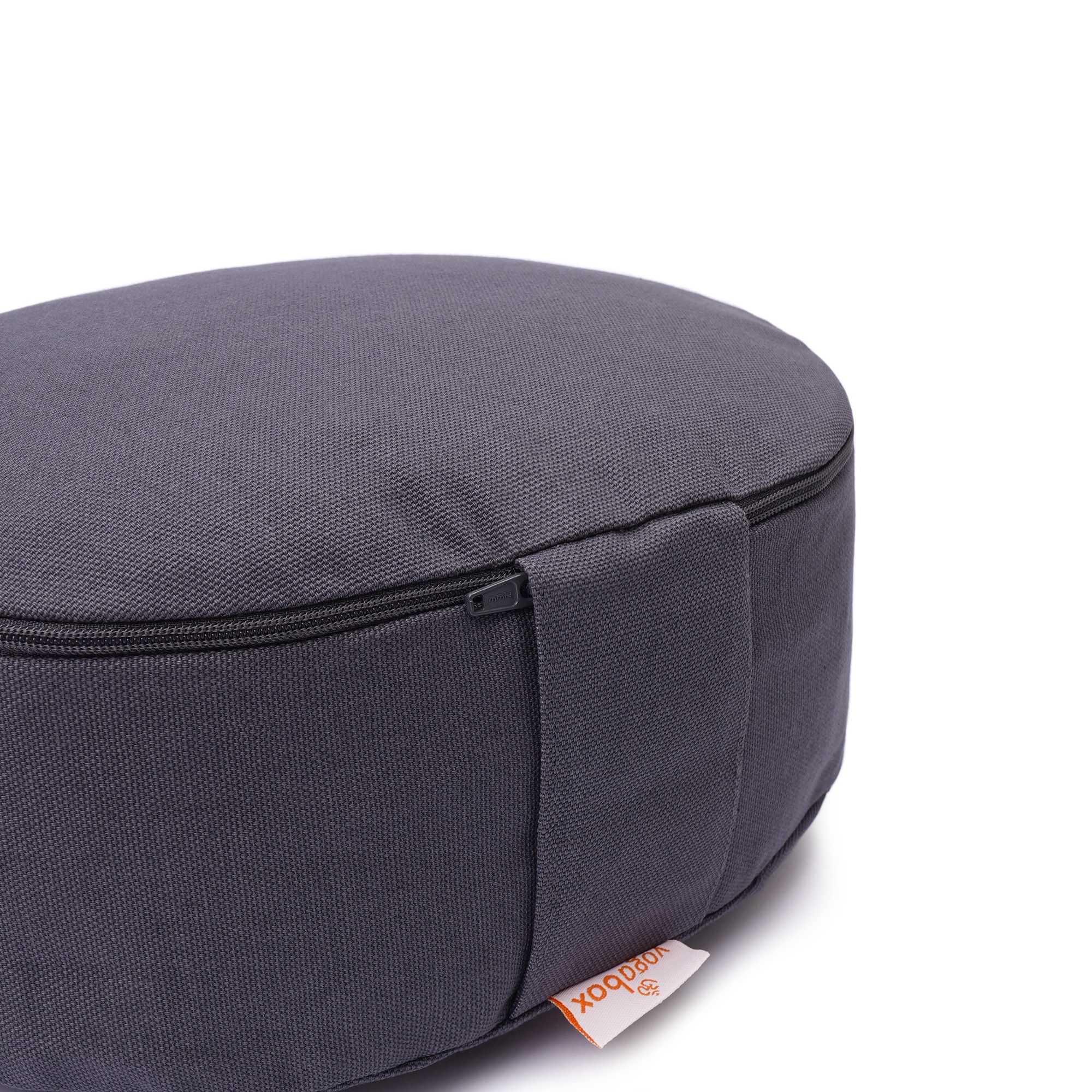 Detailansicht eines grauen Meditationskissens mit sichtbarer Reißverschlussnaht und Yogabox-Label.