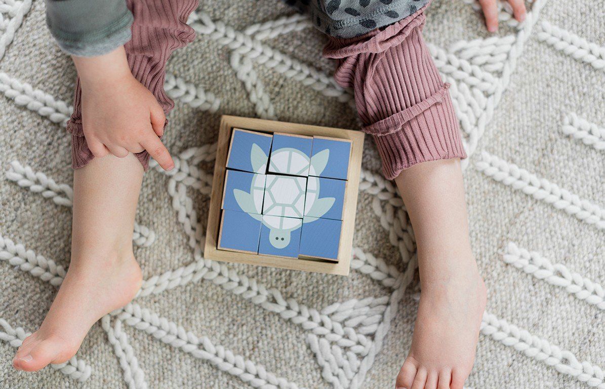 Holzwürfel-Puzzle mit Schildkröten-Motiv. Neun Würfel bilden ein Bild in einem Holzrahmen. Blau und weiß.