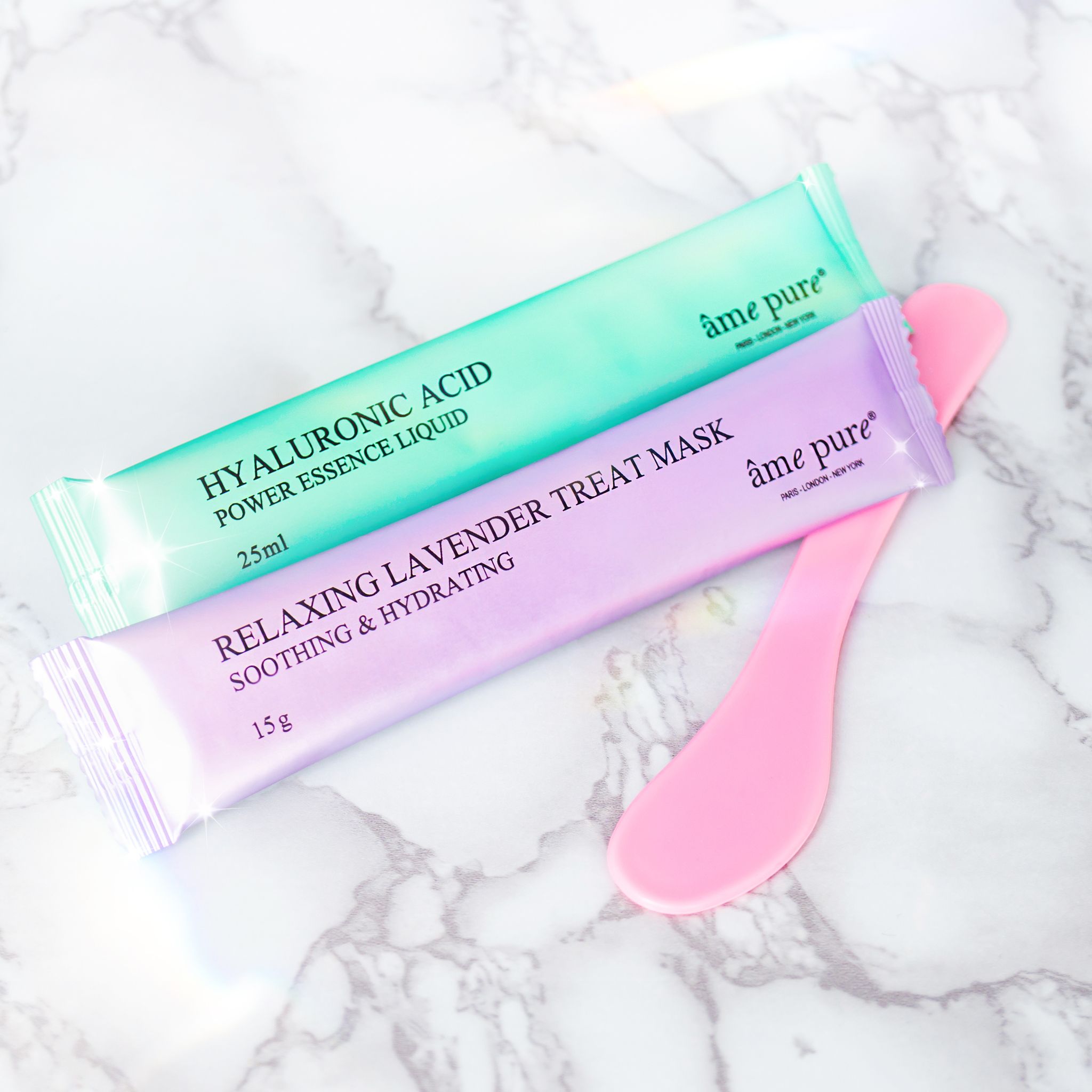 Twee zakjes. Groen: Hyaluronic Acid, Power Essence Liquid, 25ml. Paars: Relaxing Lavender Treat Mask, 15g. Merk: âme pure.