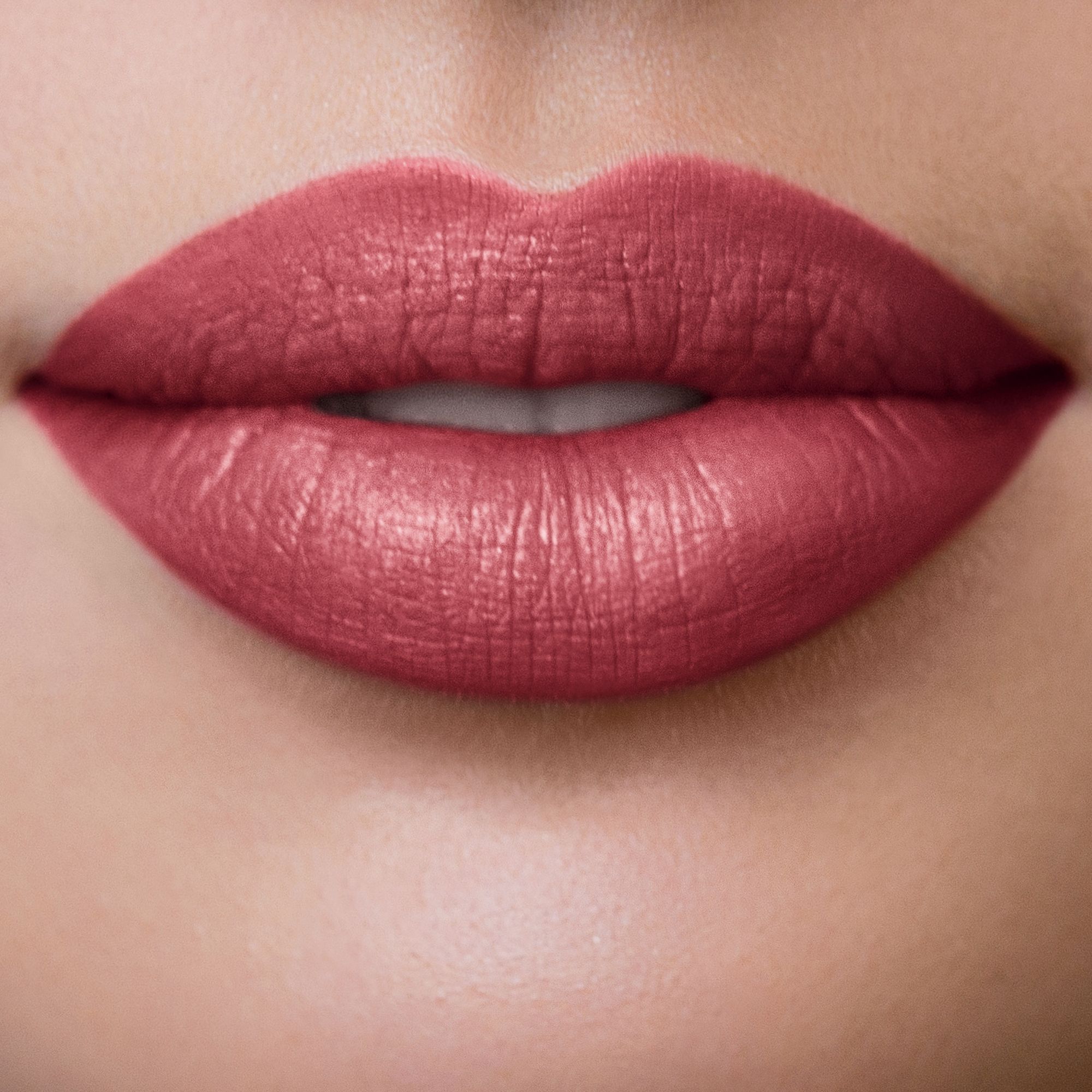 Nahaufnahme von Lippen, die mit rosafarbenem Lippenstift geschminkt sind. Die Lippen sind geöffnet.