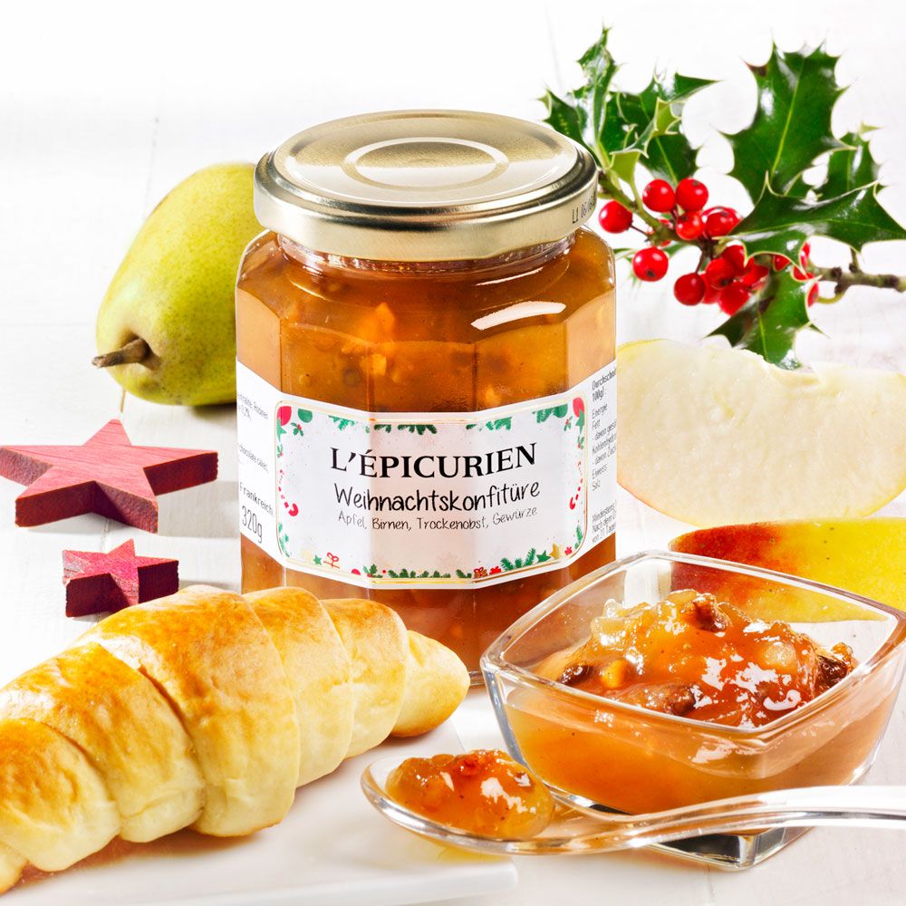 Glas L'Épicurien Weihnachtskonfitüre, daneben Croissant, Birne, Apfelstücke, Konfitüre in Schale und Löffel.