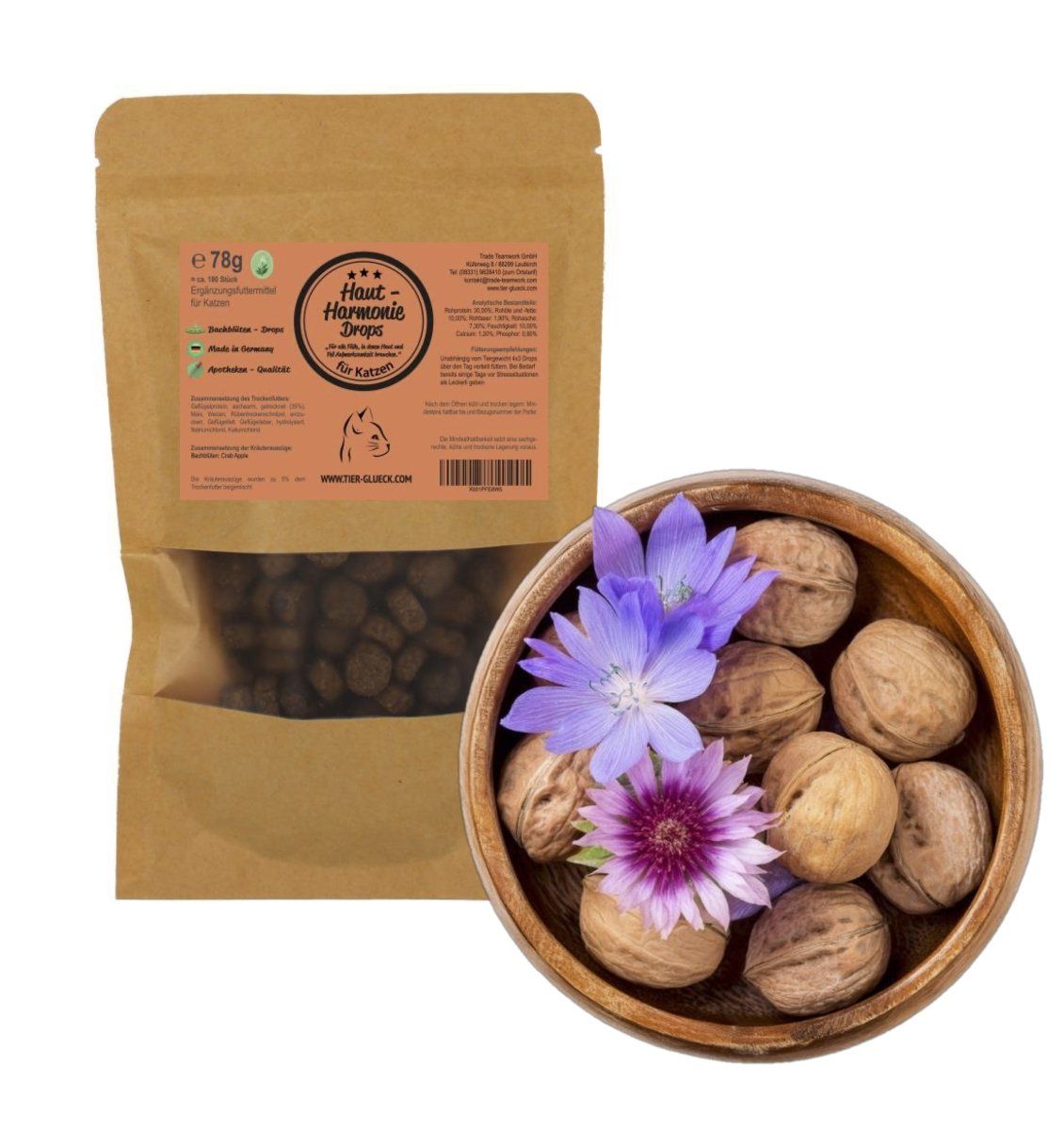 Beutel TierGlück Haut-Harmonie Drops neben Schale mit Walnüssen und Blüten. Produkt durch Fenster sichtbar.