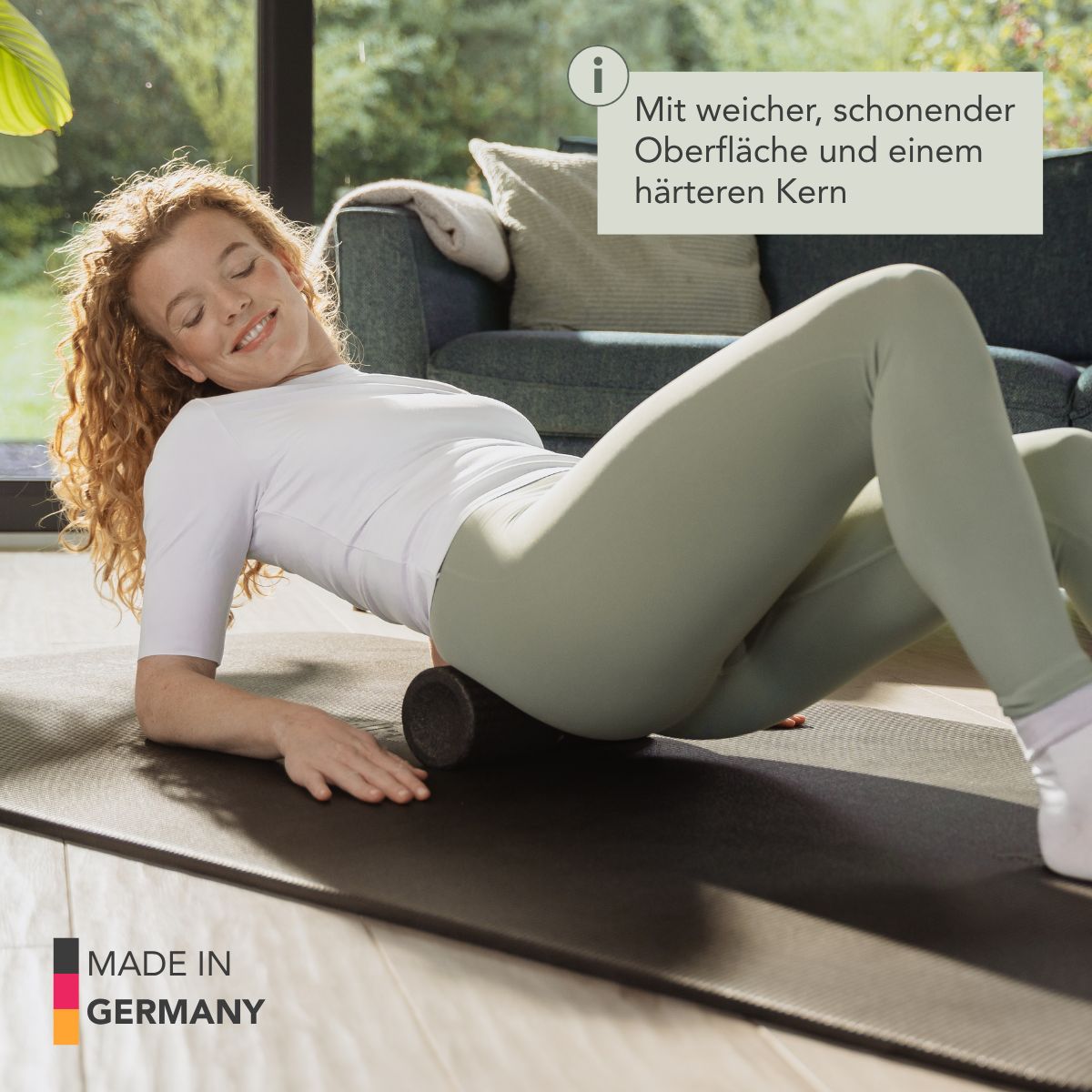 Frau liegt auf Matte und massiert den Rücken mit einer schwarzen Faszienrolle.