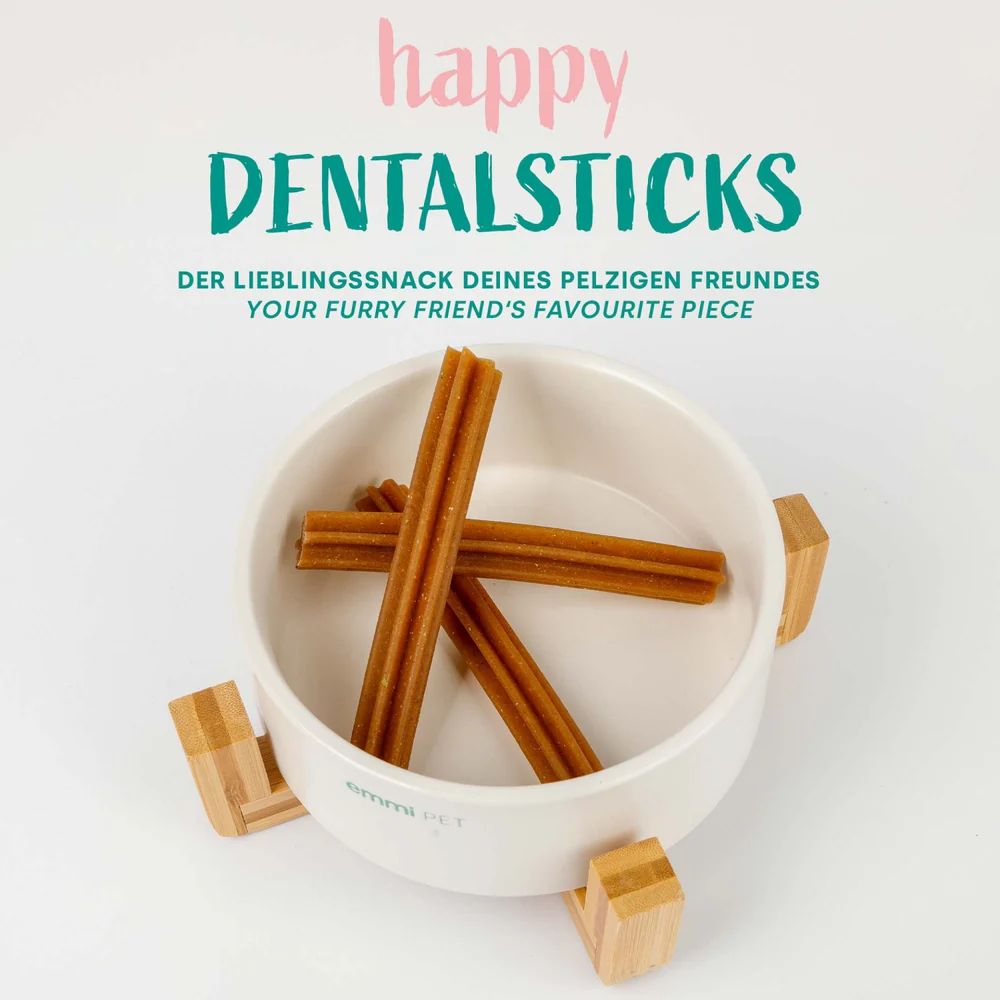 Drei braune Sticks in einer weißen Schale mit Holzfüßen. Auf der Schale steht "emmi-pet".