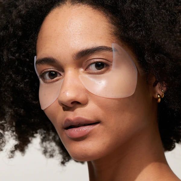 Frau mit Augenpads auf der Haut. Pads transparent, bedecken Augenpartie. Haut glatt.