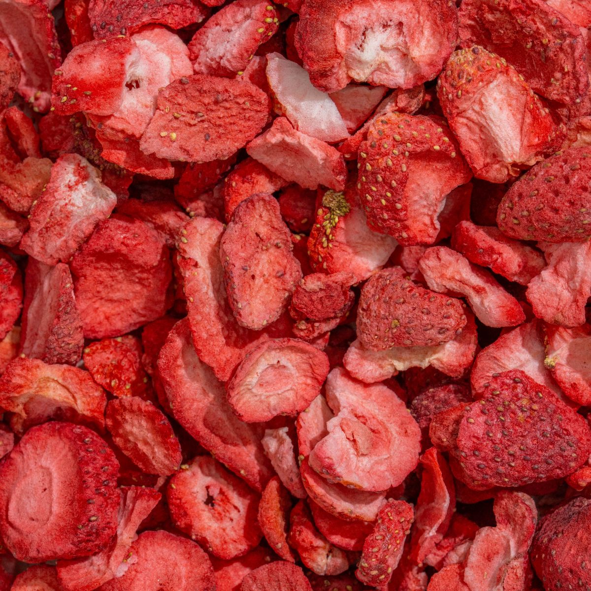 Nahaufnahme gefriergetrockneter Erdbeeren. Rote, unregelmäßig geformte Stücke. Einige mit Kernen.