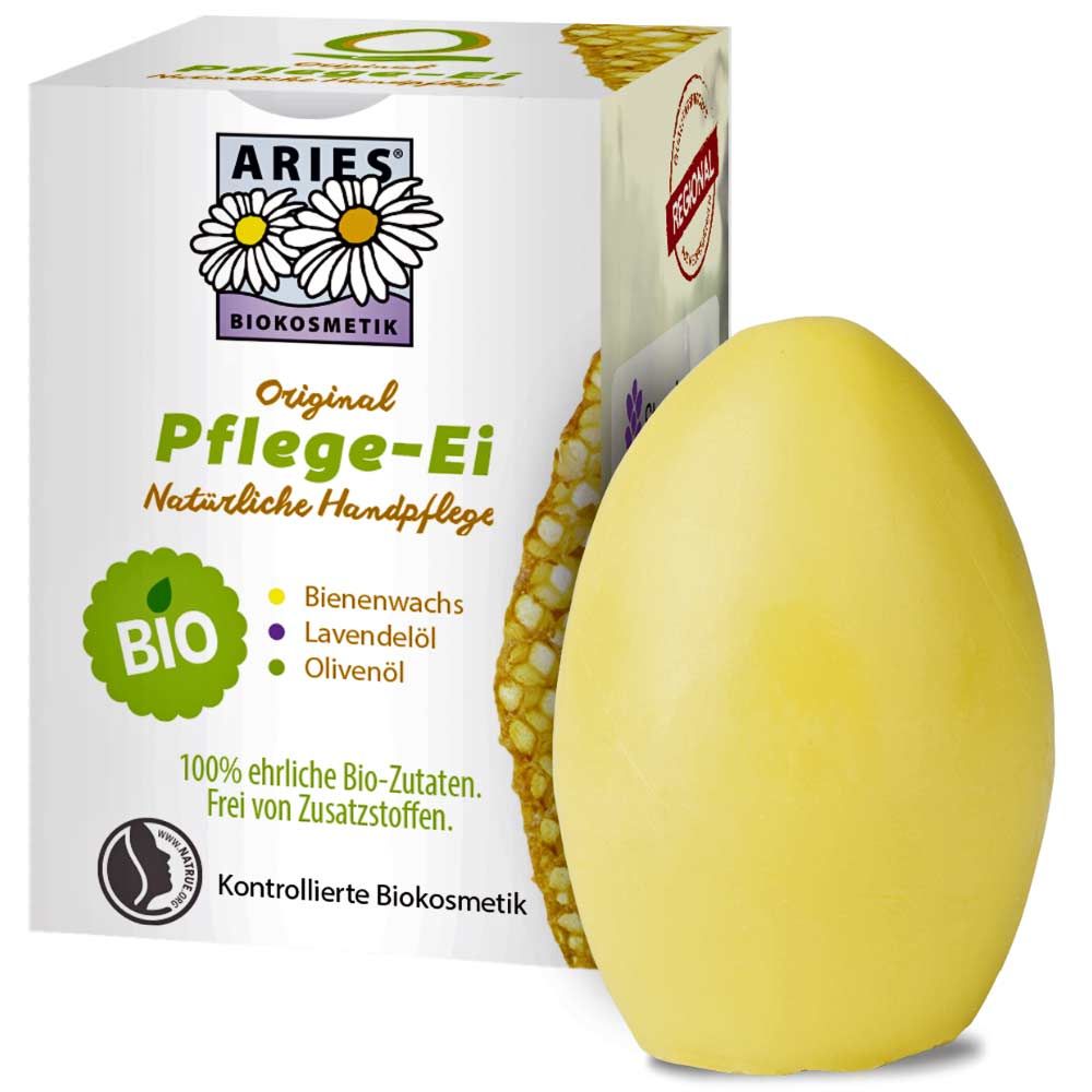 Gelbes Pflege-Ei neben Verpackung. Verpackung mit Logo, Schriftzug 'Pflege-Ei', 'BIO' Siegel. Enthält Bienenwachs, Lavendelöl, Olivenöl.