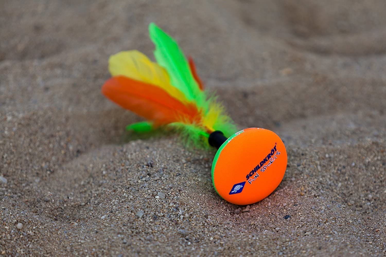Peteca-Shuttle auf Sand. Orangefarbener Boden mit Logo. Gelbe, grüne und orangefarbene Federn.