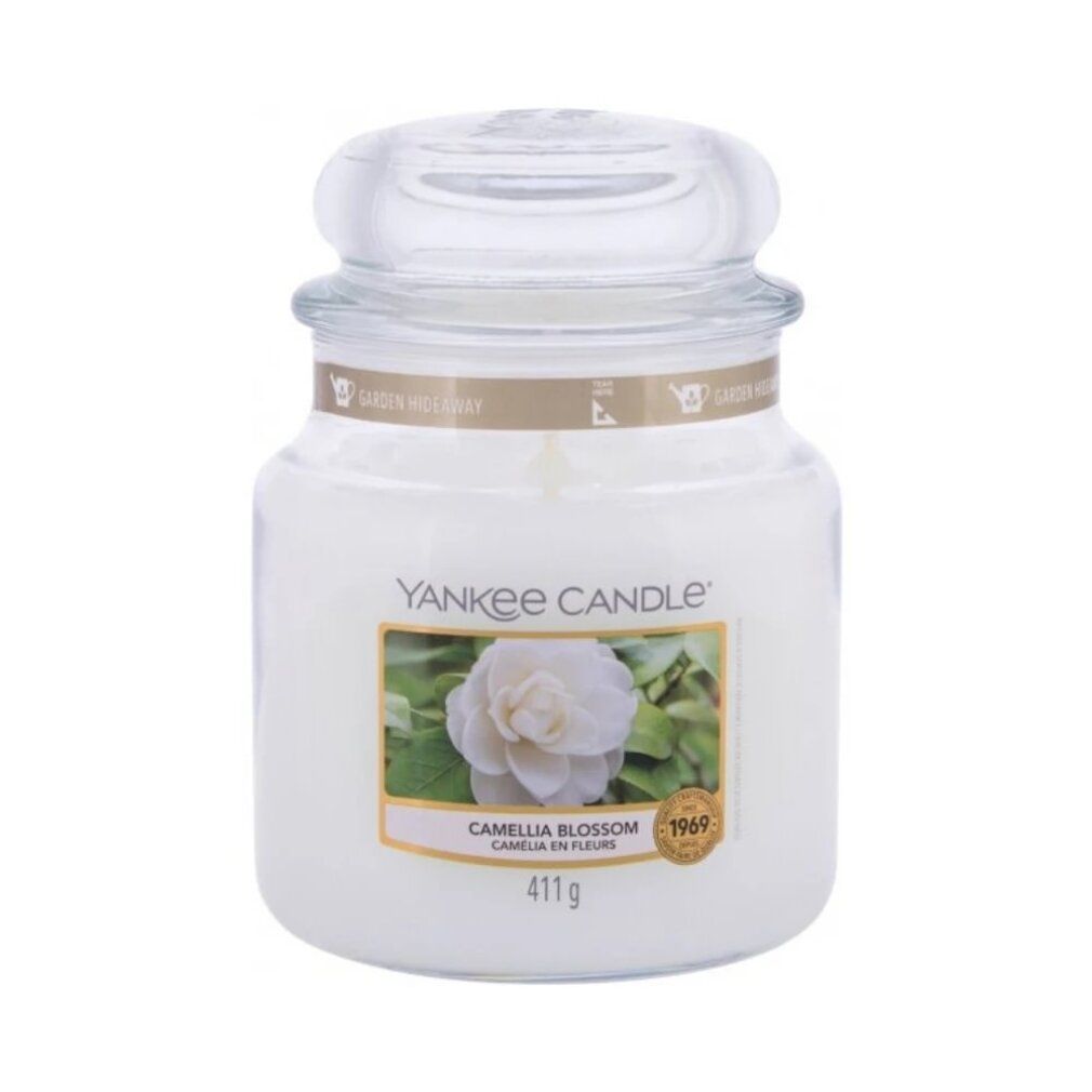 Weißes Kerzenglas mit Deckel. Etikett mit Blüte und Schriftzug. Aufschrift: Yankee Candle, Camellia Blossom, 411g.