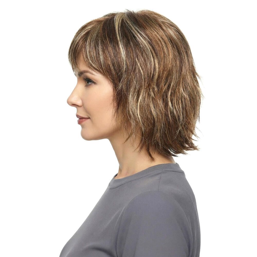 Profil einer Frau mit brauner Perücke mit Pony und blonden Strähnen. Graues T-Shirt.