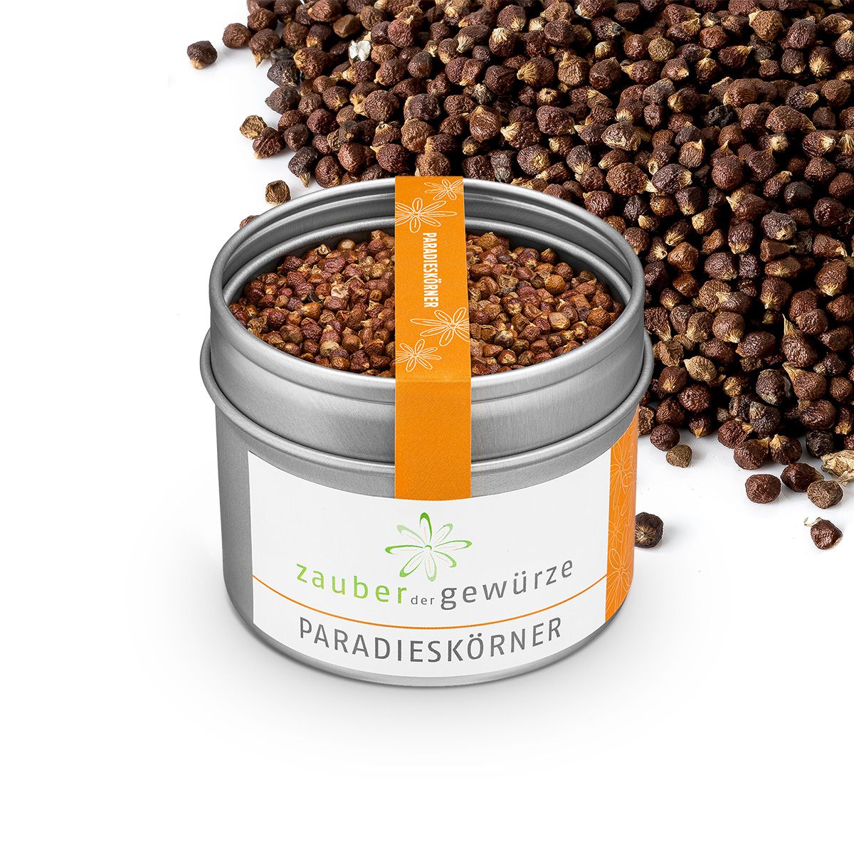 Geöffnete, silberne Dose mit Paradieskörnern. Orangefarbenes Etikett. Weißes Etikett mit Logo und Schriftzug. Streuung von Körnern.
